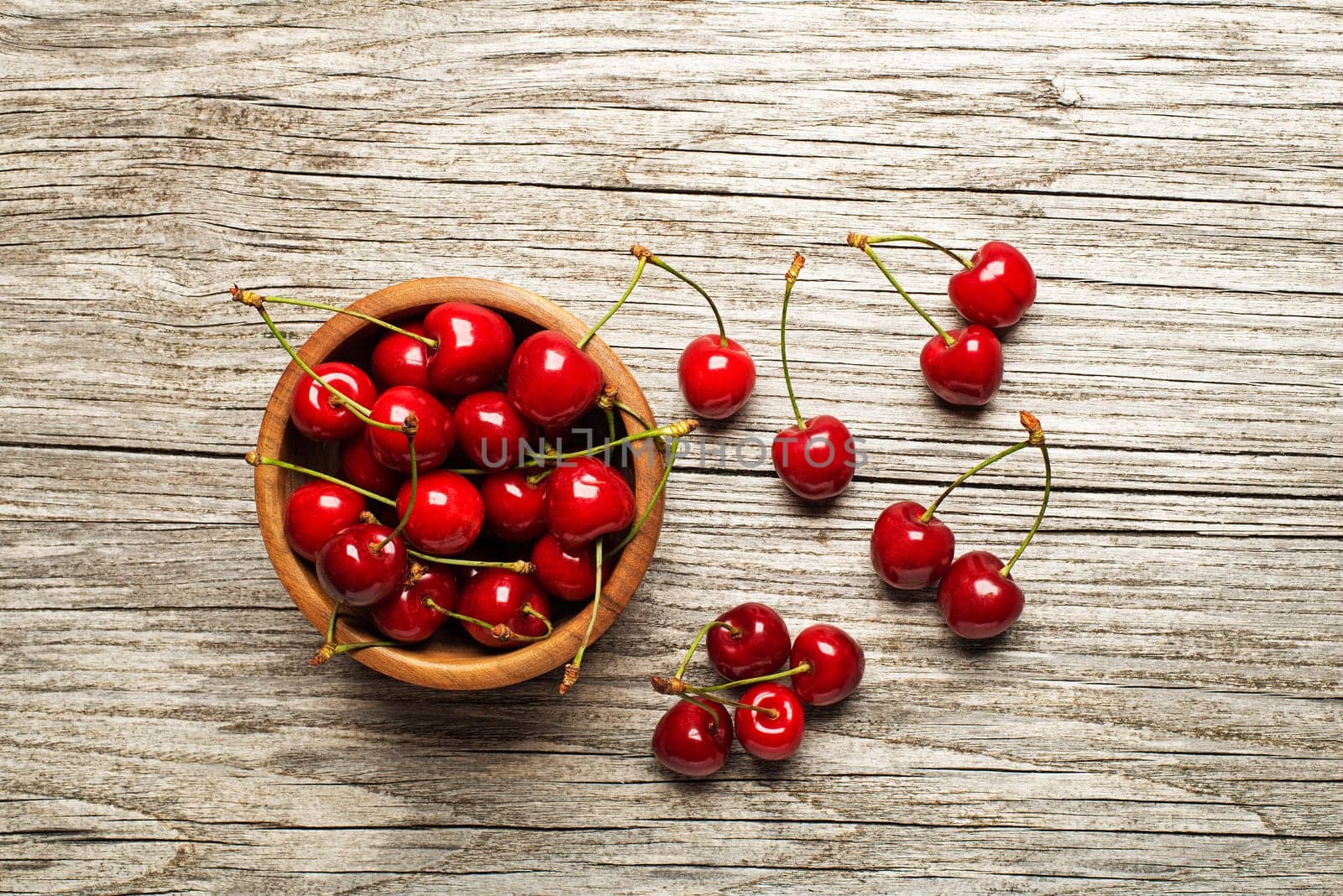 Fresh cherries in a bowl on wooden table.