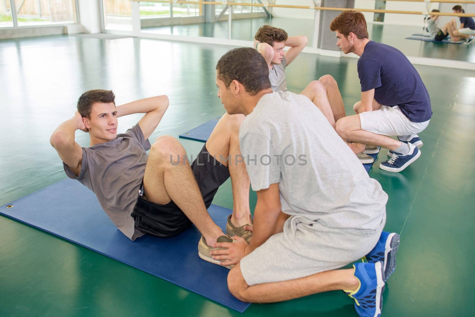Two men holding feet of friends doing situps