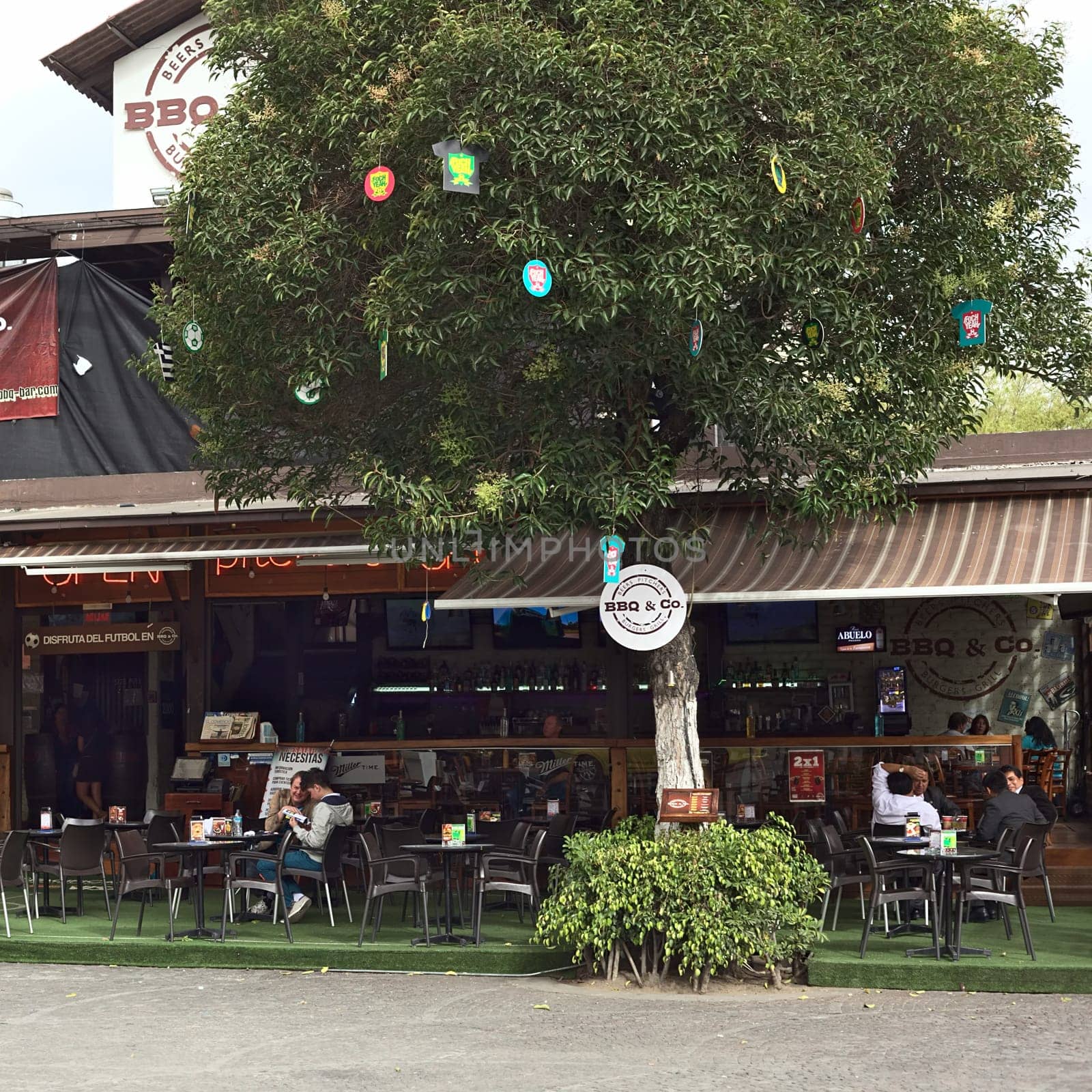 QUITO, ECUADOR - AUGUST 6, 2014: Unidentified people sitting at the BBQ & Co bar and restaurant on Plaza Foch in the tourist district La Mariscal on August 6, 2014 in Quito, Ecuador. Plaza Foch is situated at the intersection of the streets Reina Victoria and Mariscal Foch, around which many hostels, bars, restaurants and other facilities for tourism and entertainment are located.
