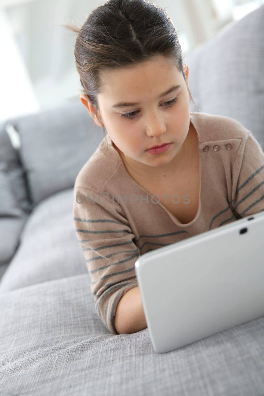 Young 8-year-old girl playing with tablet
