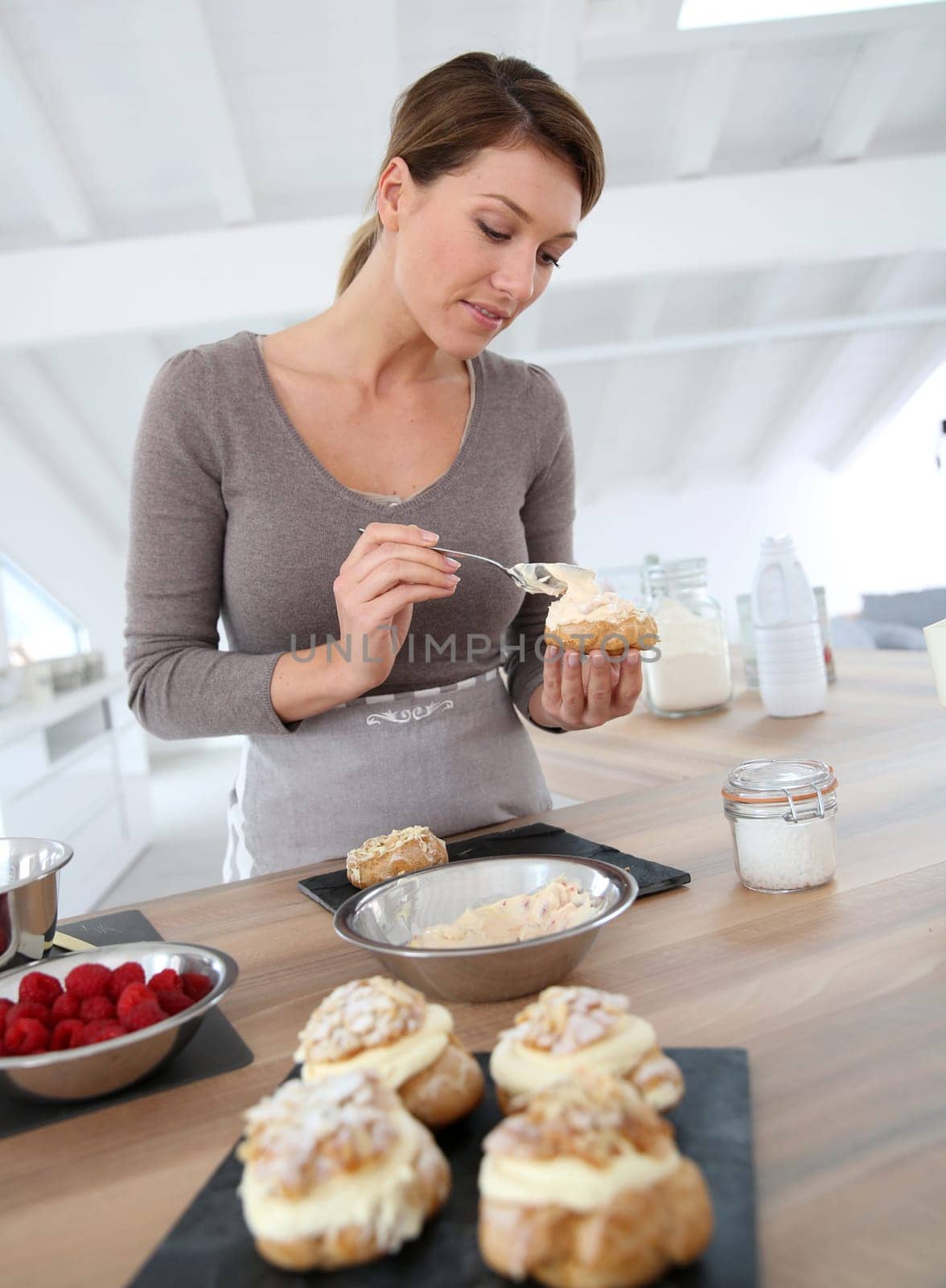 Woman in kitchen preparing cream puffs