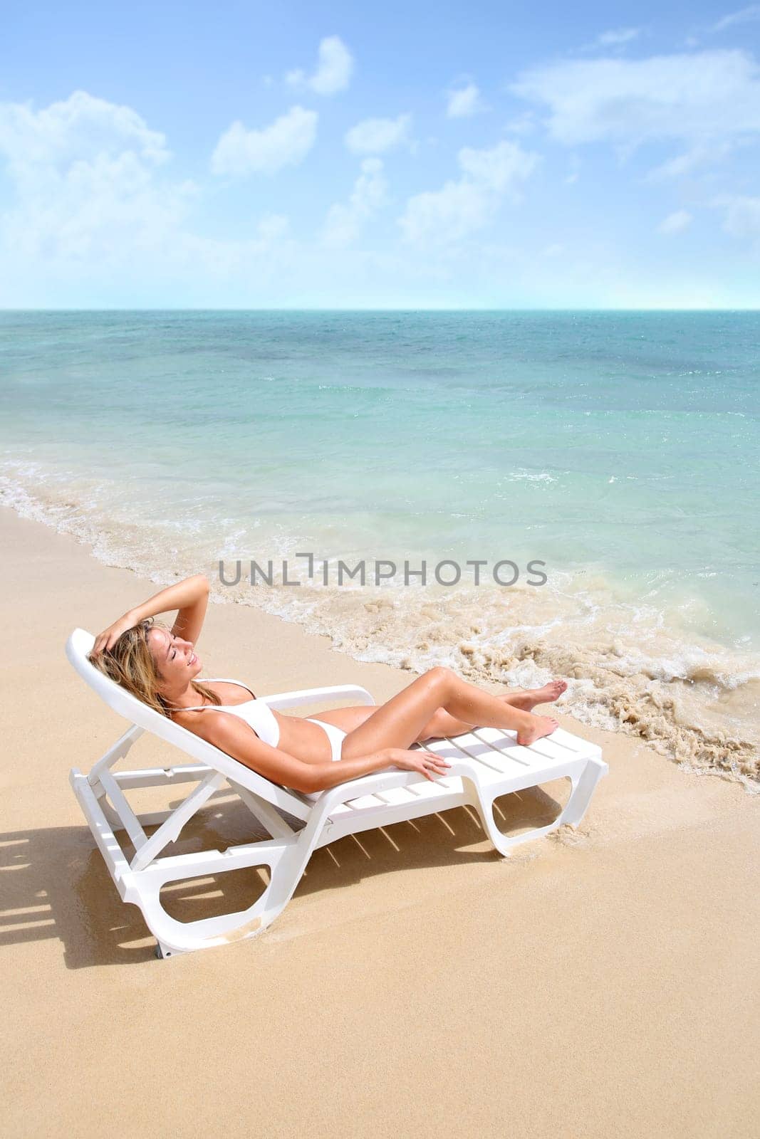 Woman relaxing in long chair by the beach