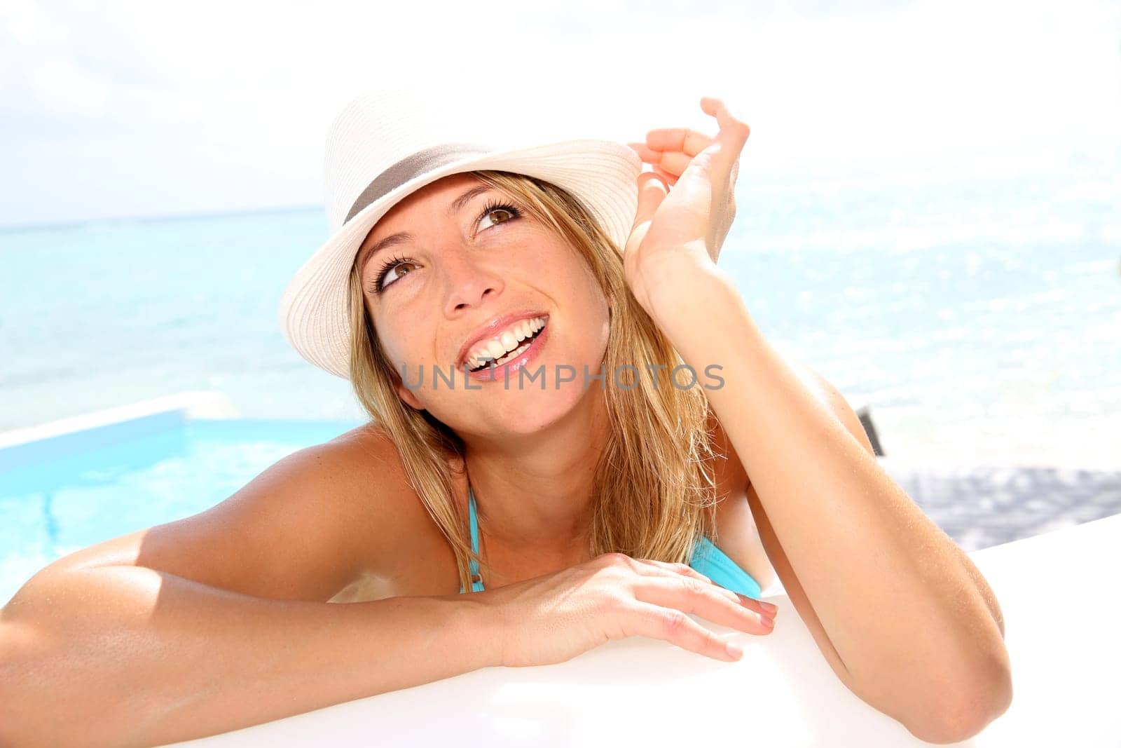 Fun girl with hat suntanning by the pool
