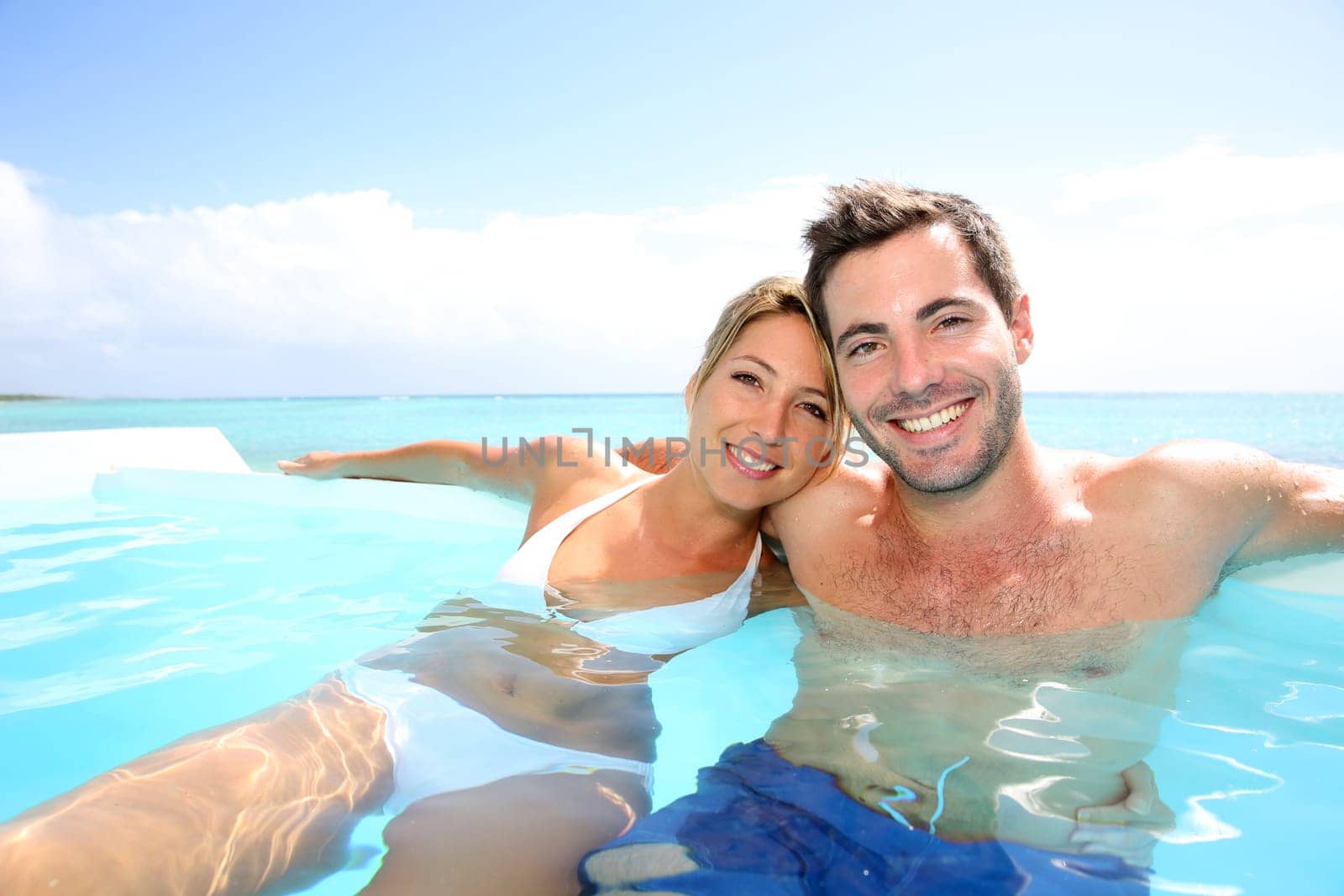 Cheerful couple swimming in infinity pool