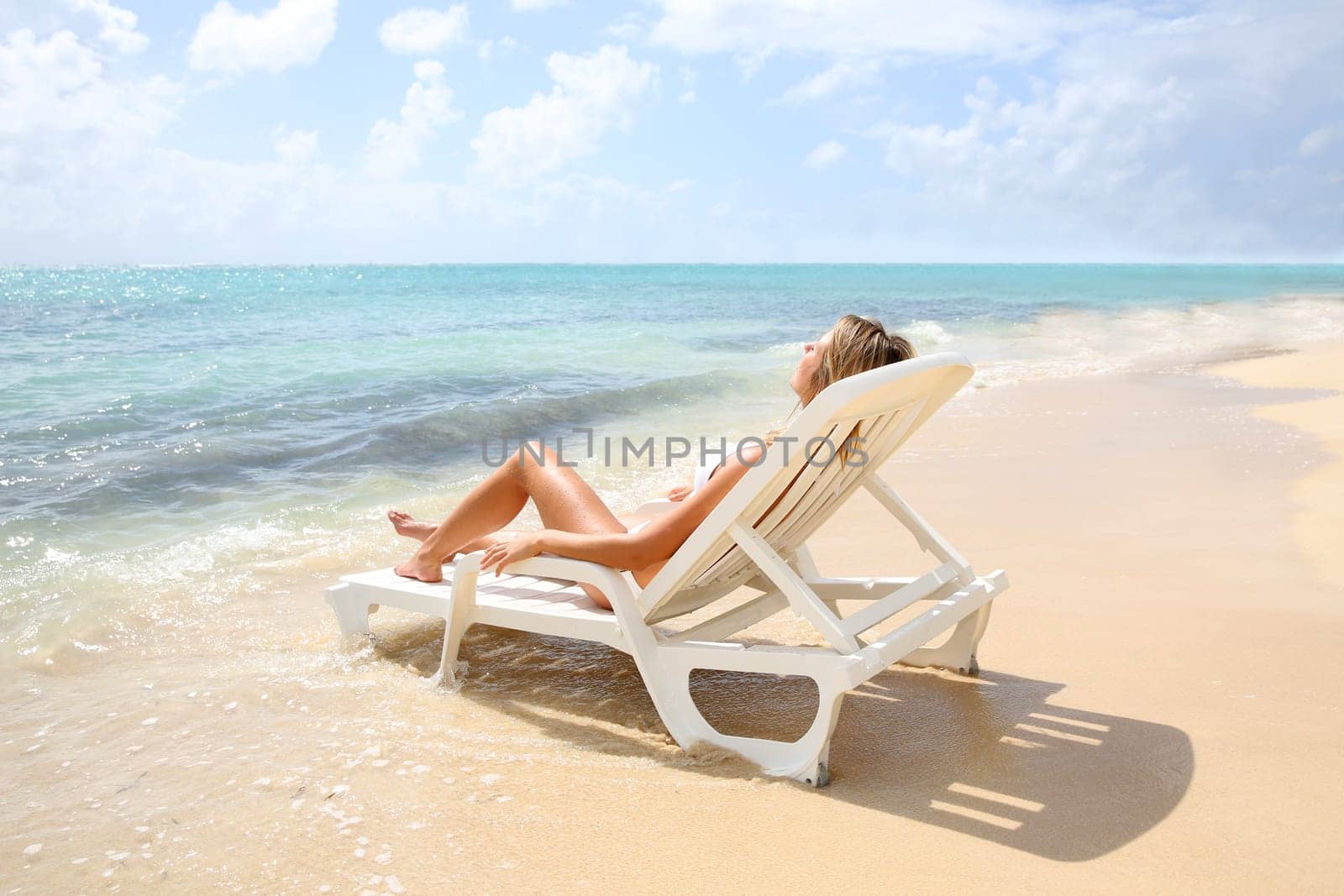 Woman relaxing in long chair by the beach
