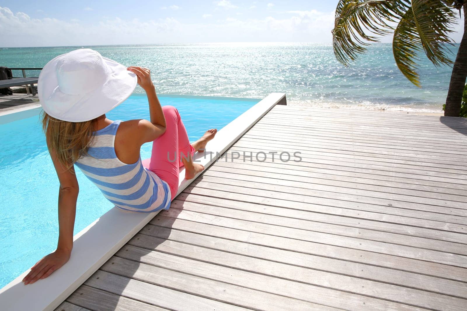 Rear view of fashion girl sitting by infinity pool