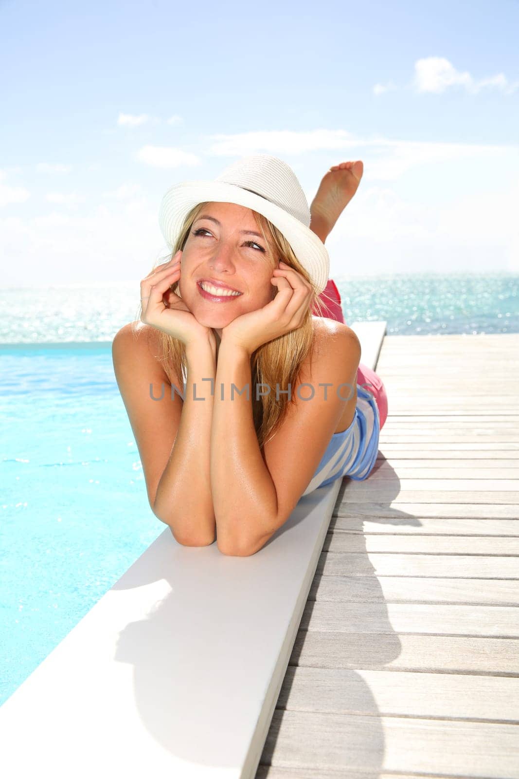 Beautiful trendy girl laying by pool on a sunny day