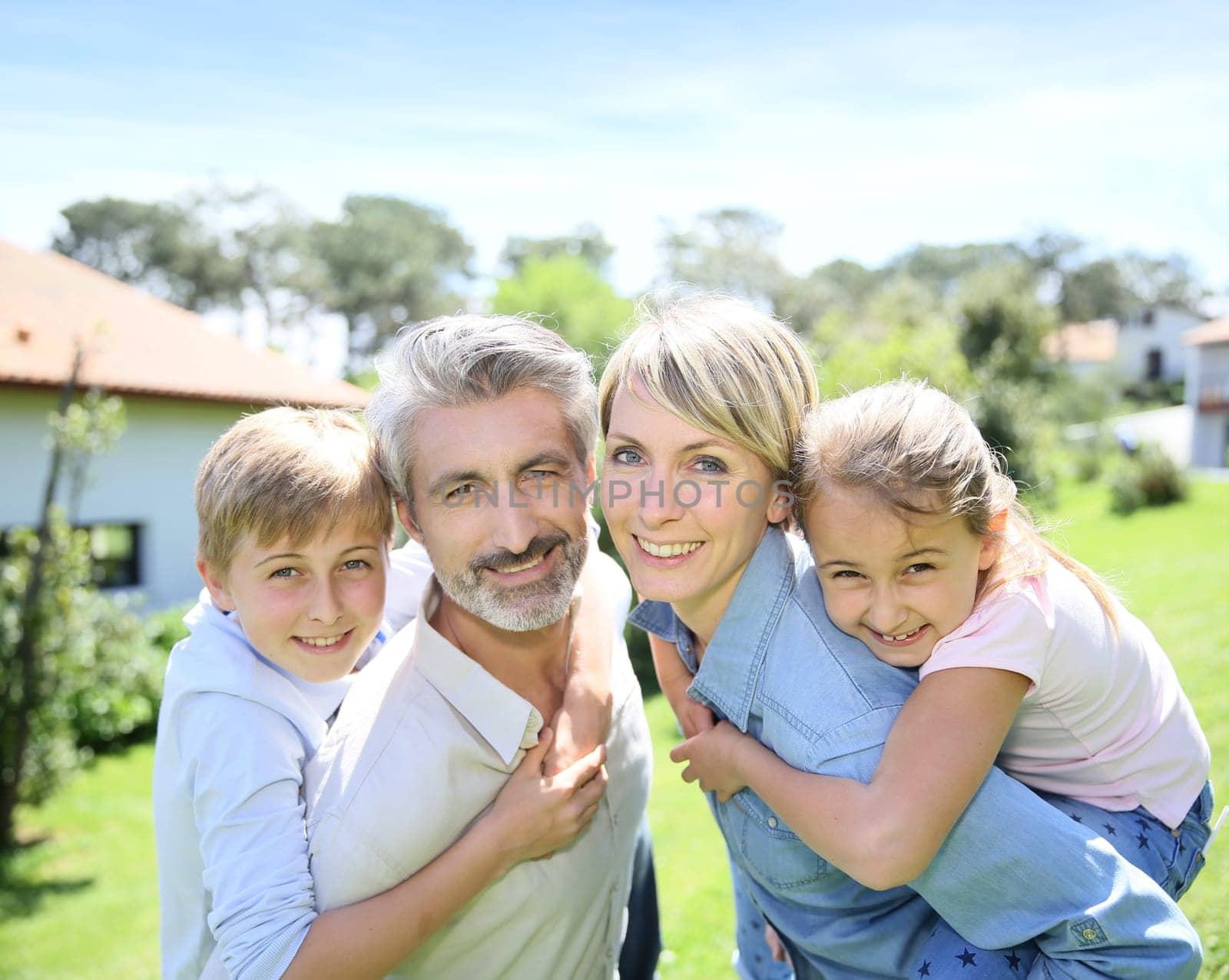 Parents giving piggyback ride to kids in garden