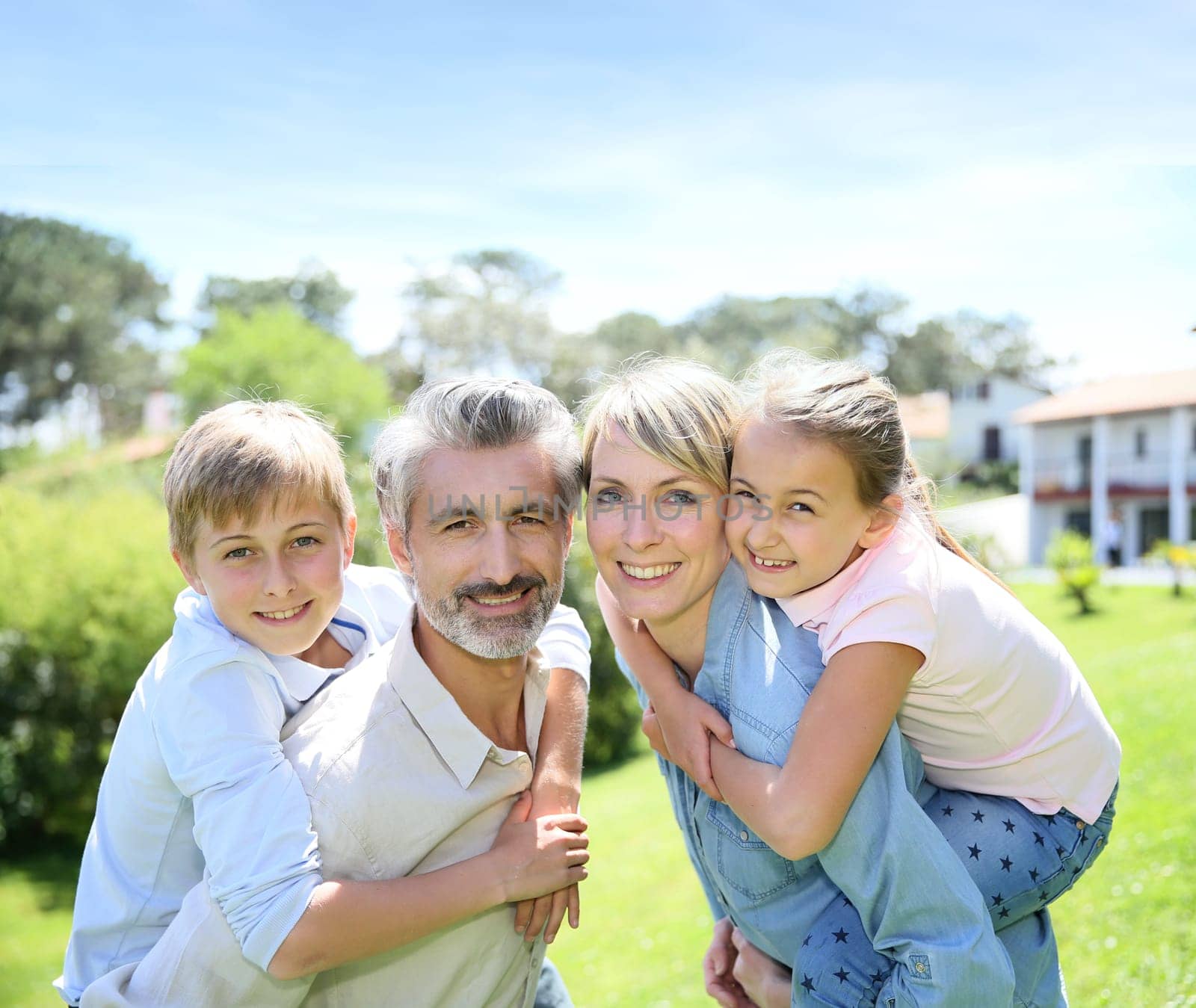 Parents giving piggyback ride to kids in garden