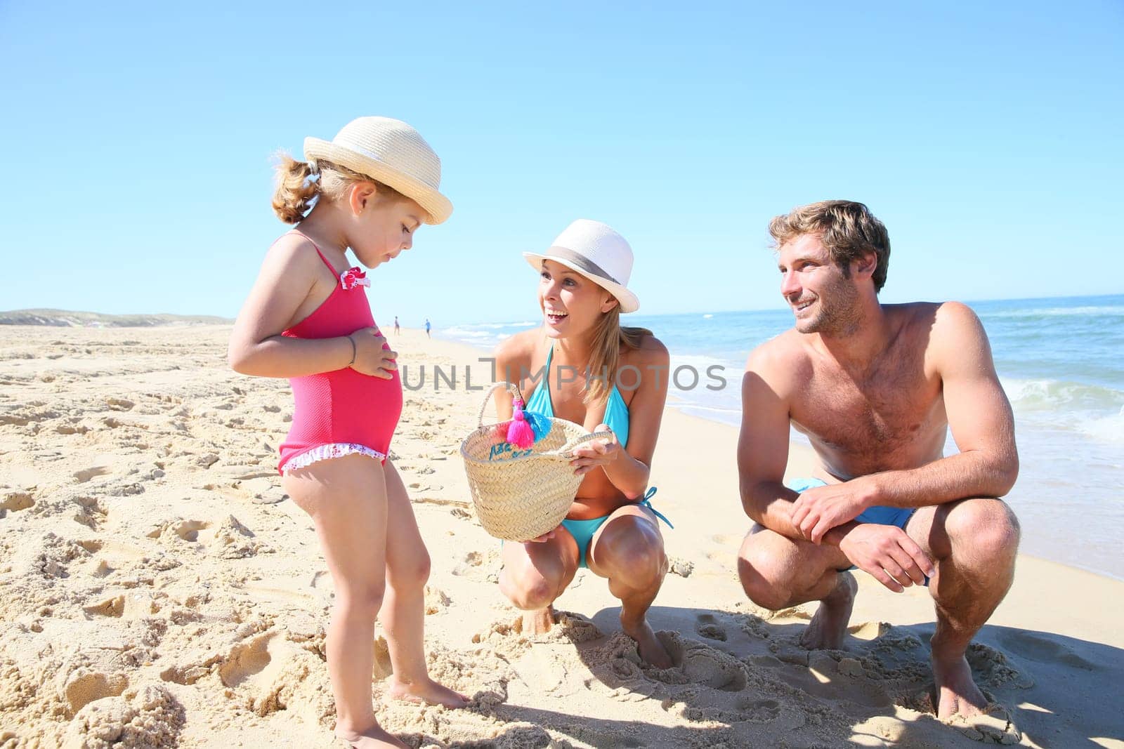 Parents with little girl playing on a sandy beach