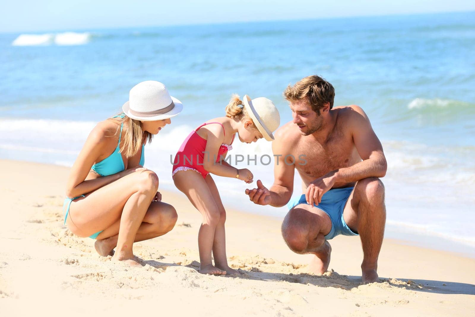 Parents with little girl playing on a sandy beach