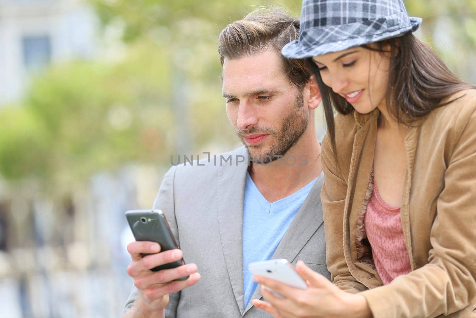 Trendy couple in town using smartphone