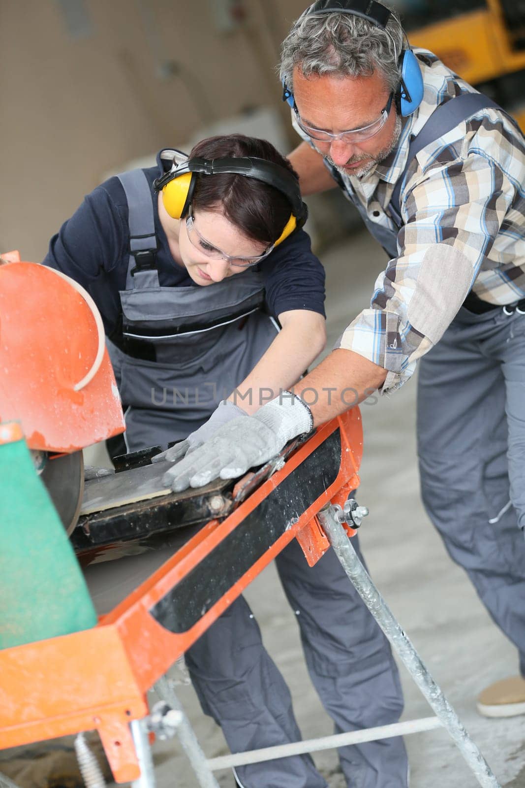 Tiler showing apprentice how to use thermal grinder