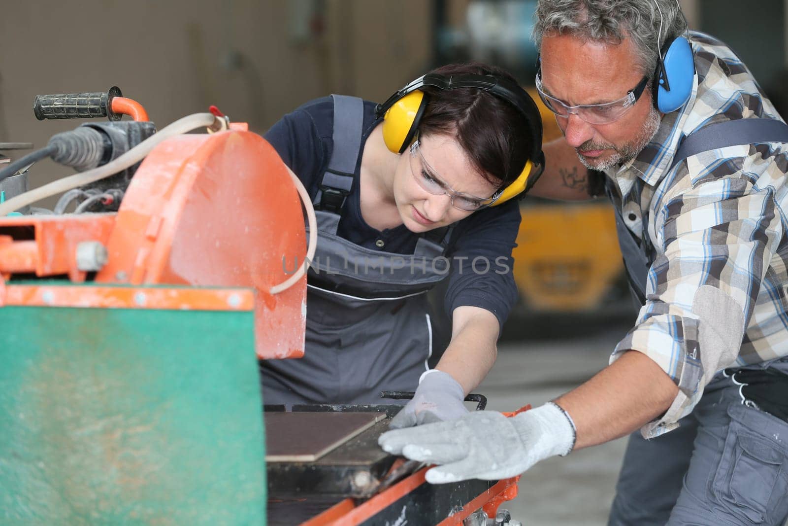 Tiler showing apprentice how to use thermal grinder