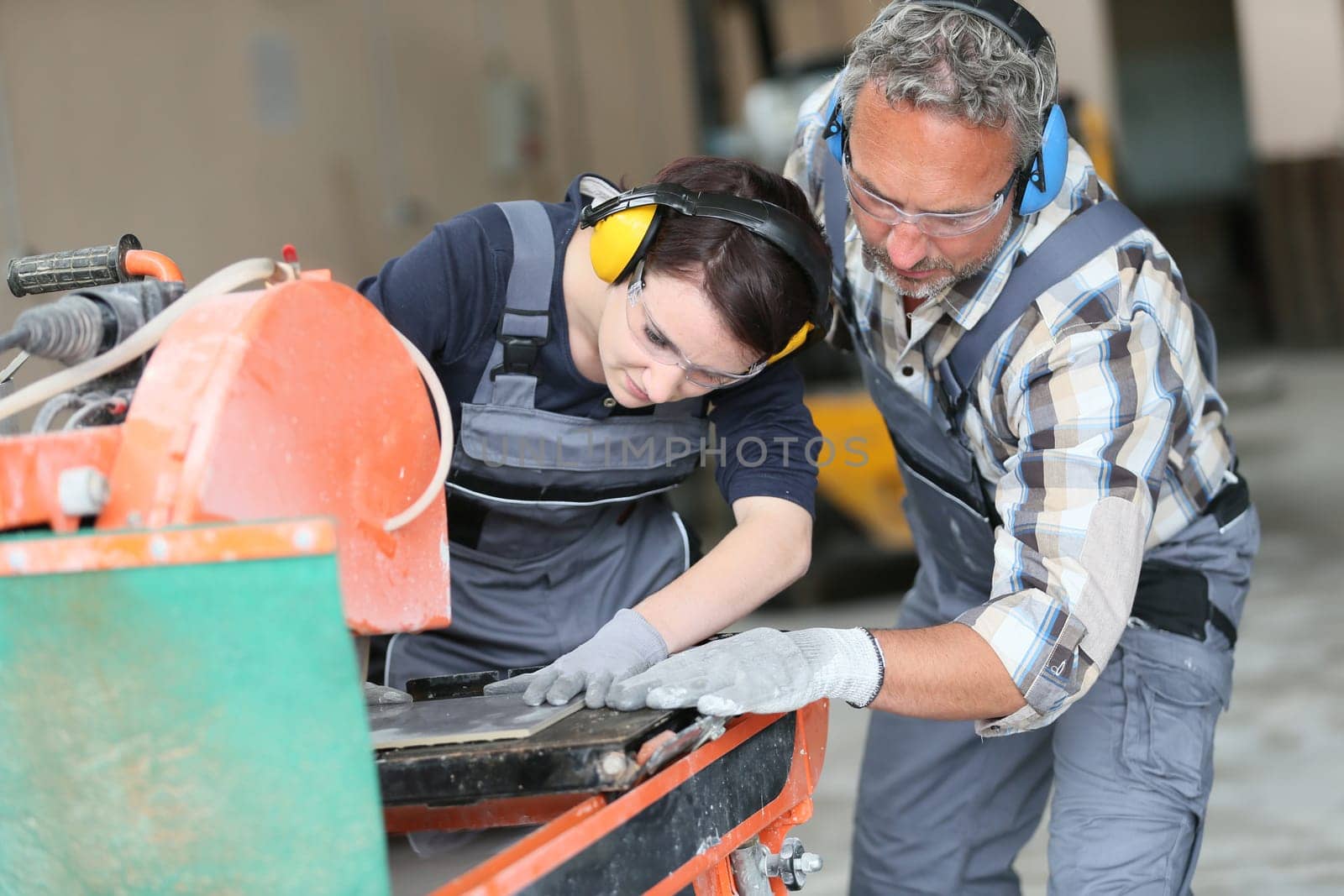 Tiler showing apprentice how to use thermal grinder