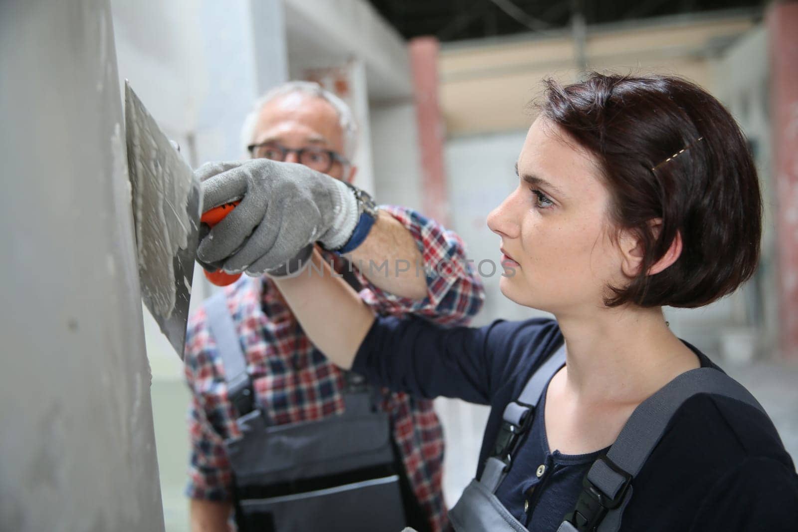 Young apprentice with professional plasterer