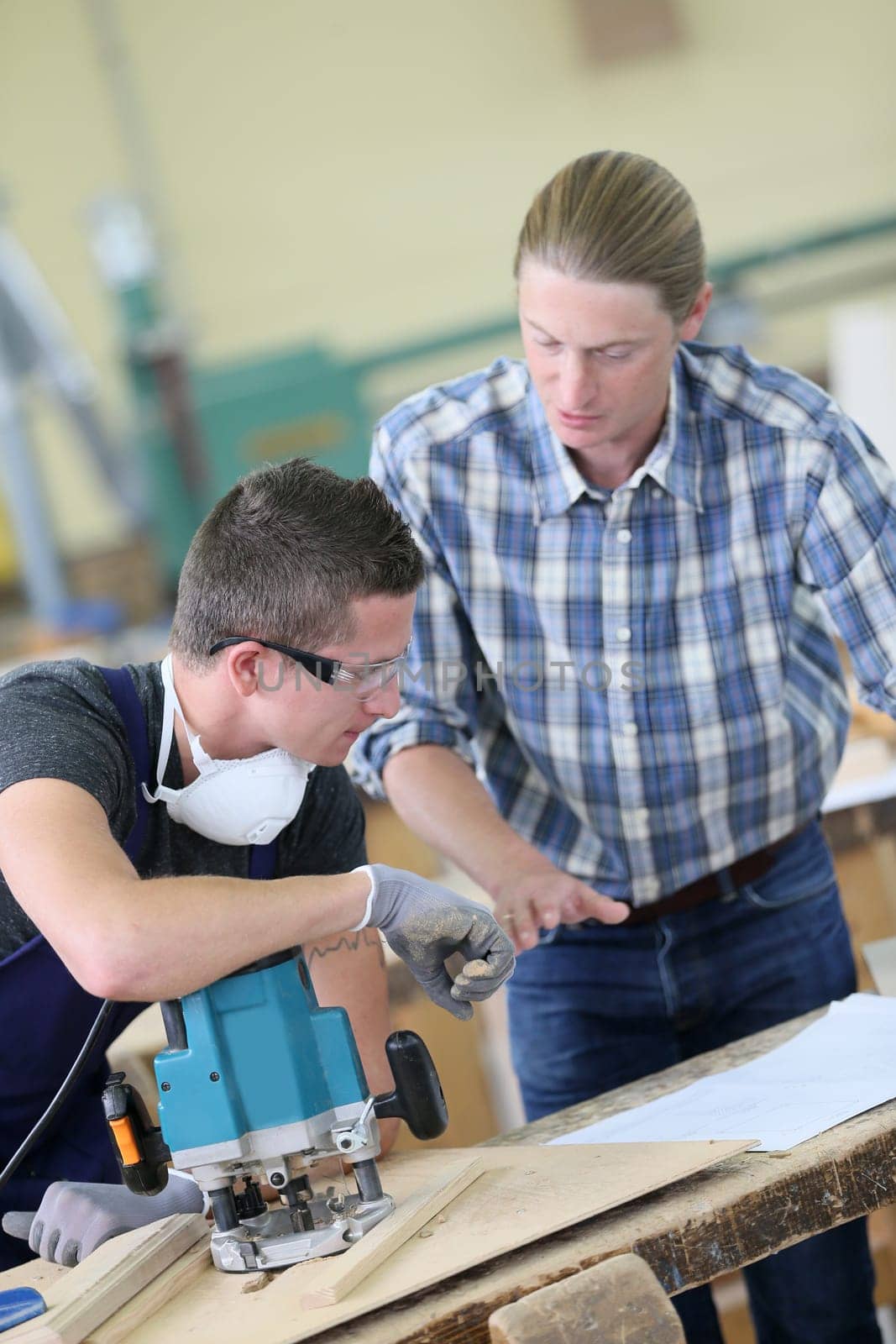 Apprentice with adult in carpentry school working on wood