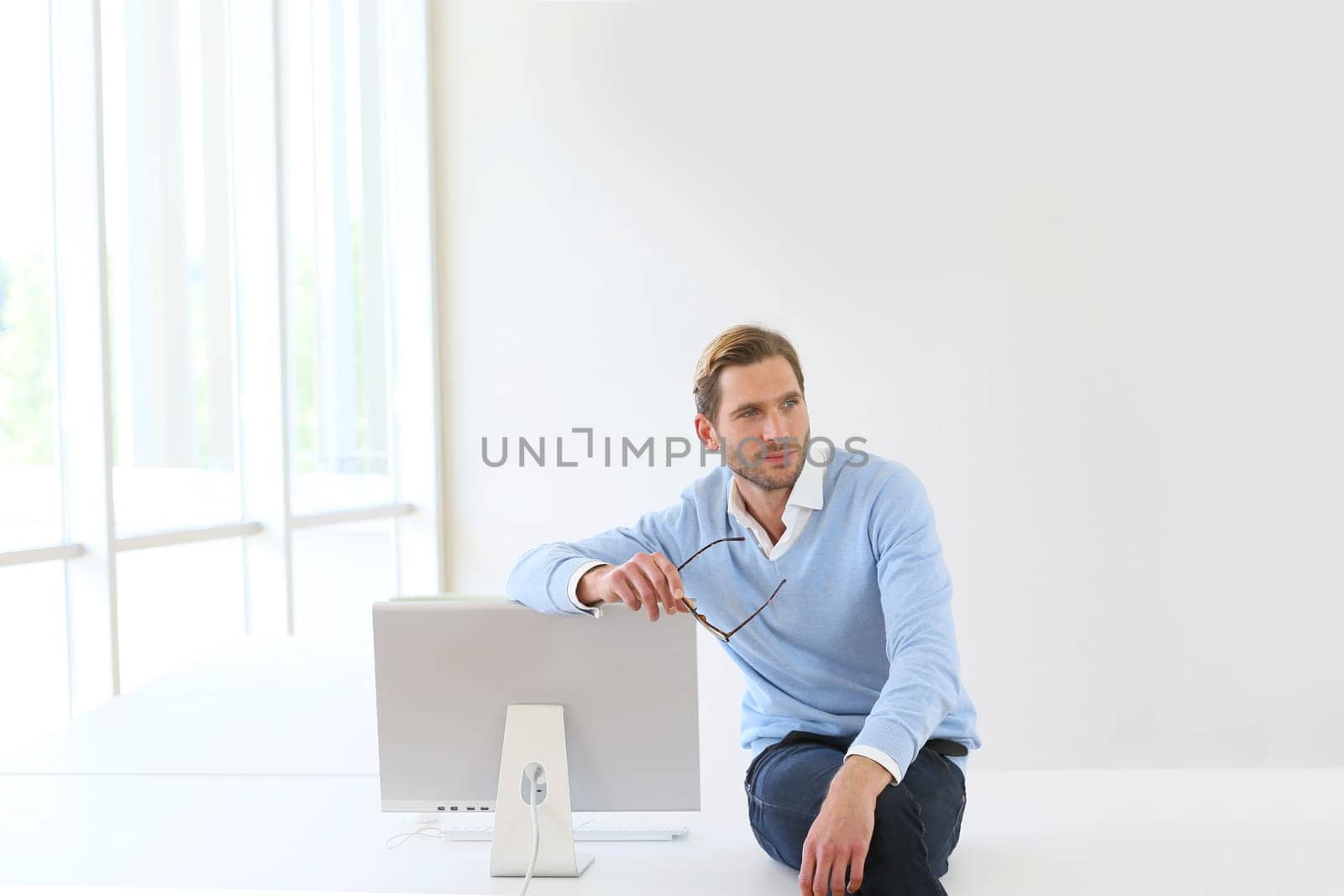Businessman sitting on table by computer in modern room