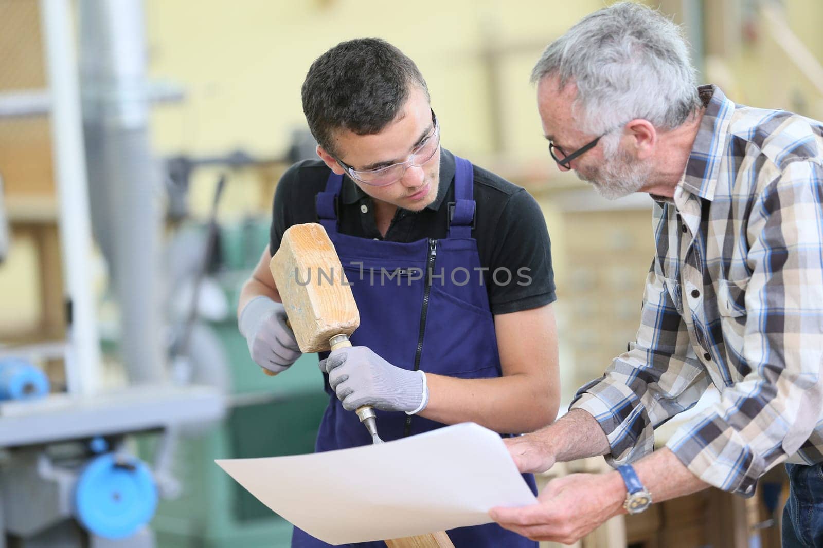 Young apprentice with teacher working on piece of wood
