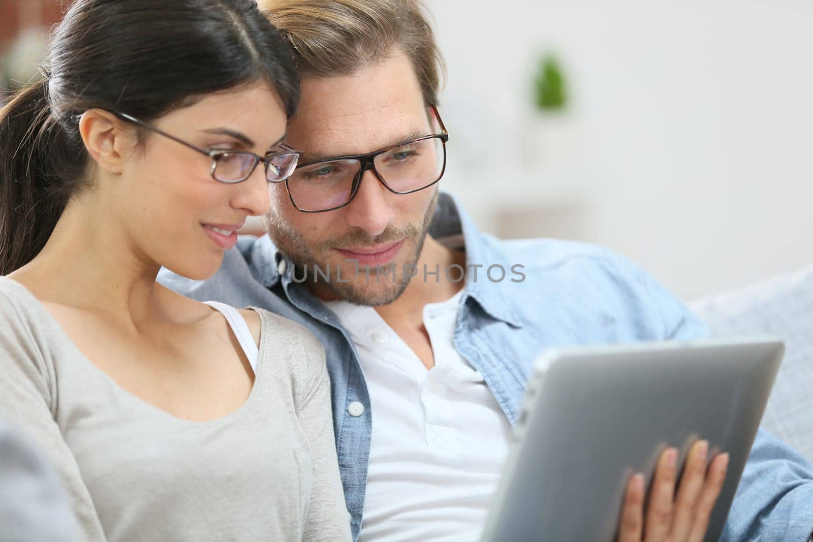 Couple with eyeglasses websurfing on tablet at home