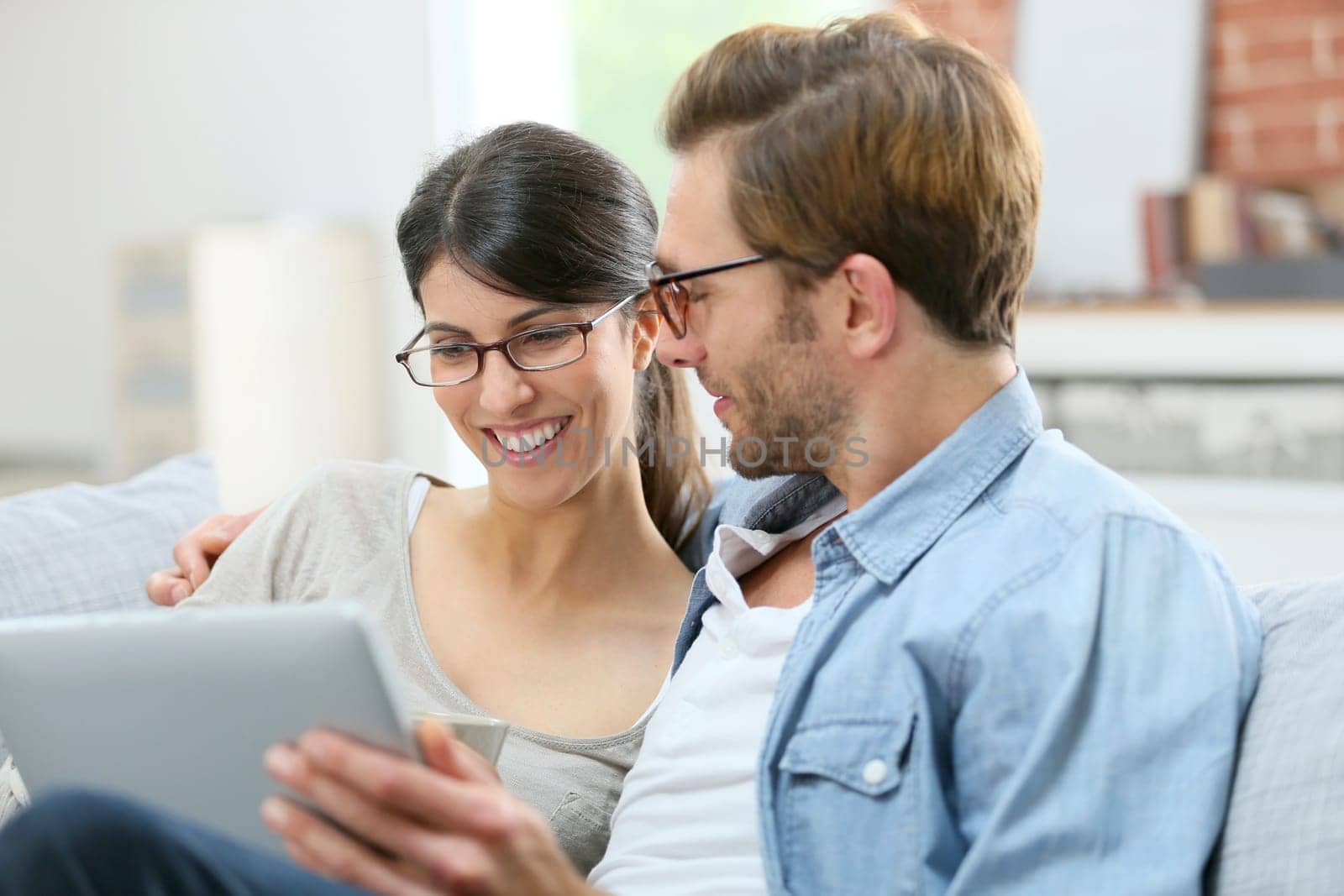 Couple with eyeglasses websurfing on tablet at home