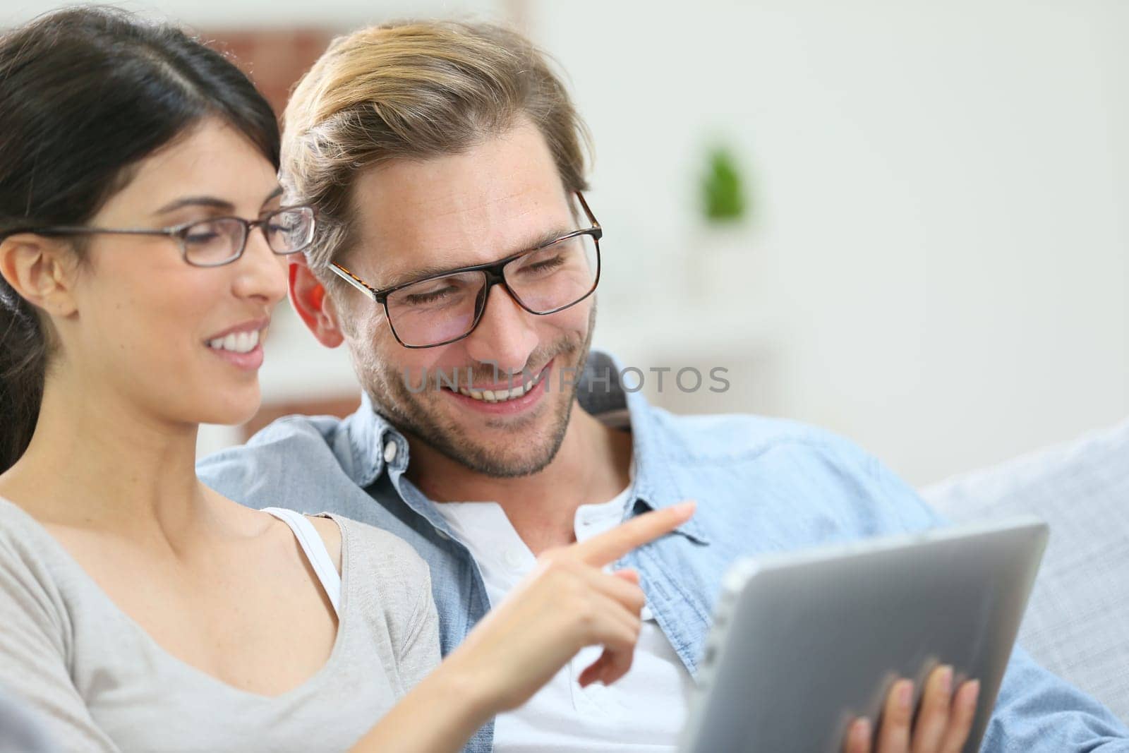 Couple with eyeglasses websurfing on tablet at home