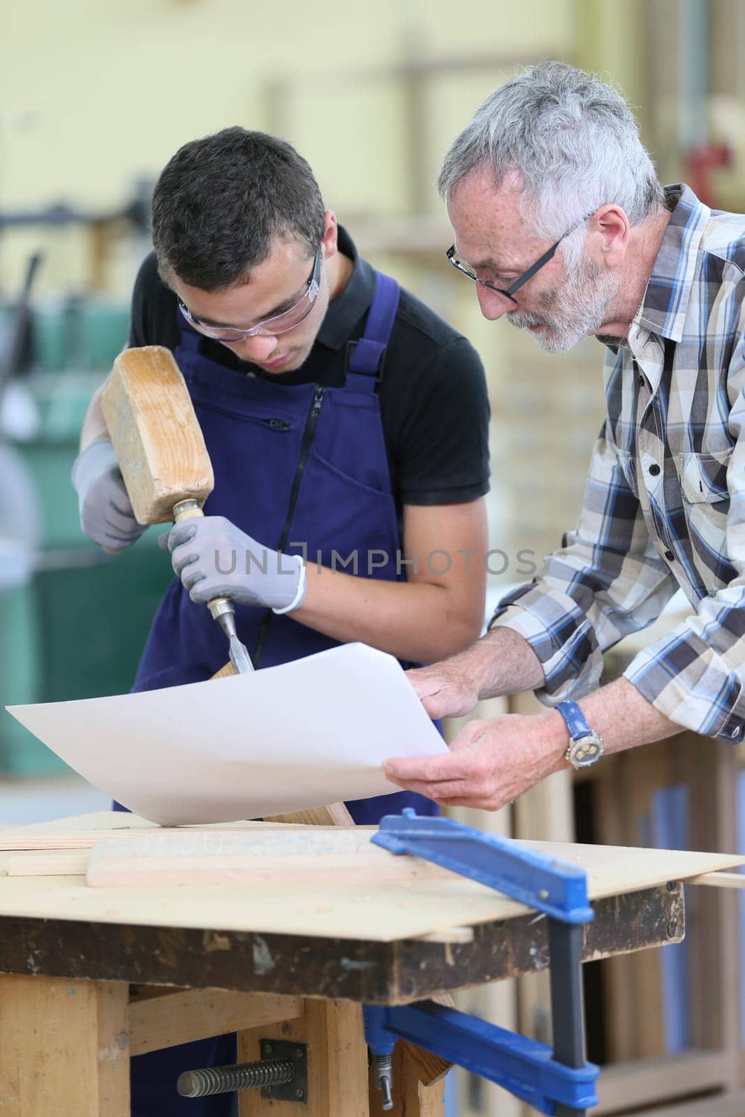 Young apprentice with teacher working on piece of wood