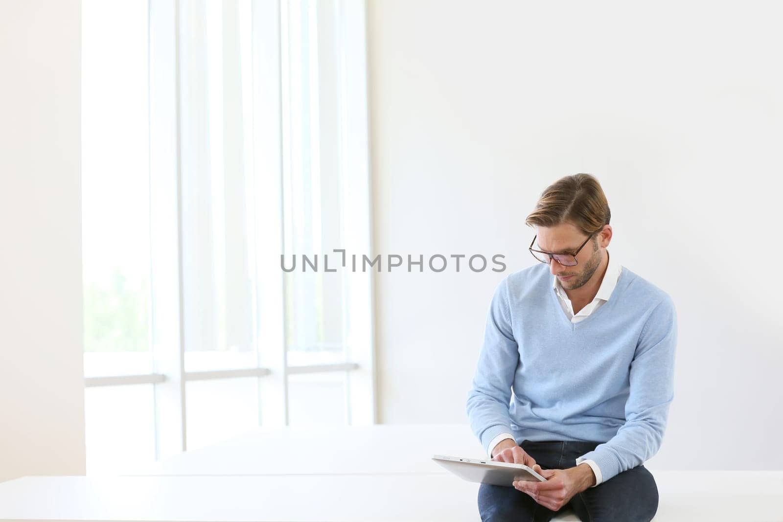 Man sitting on table, connected on digital tablet, white background