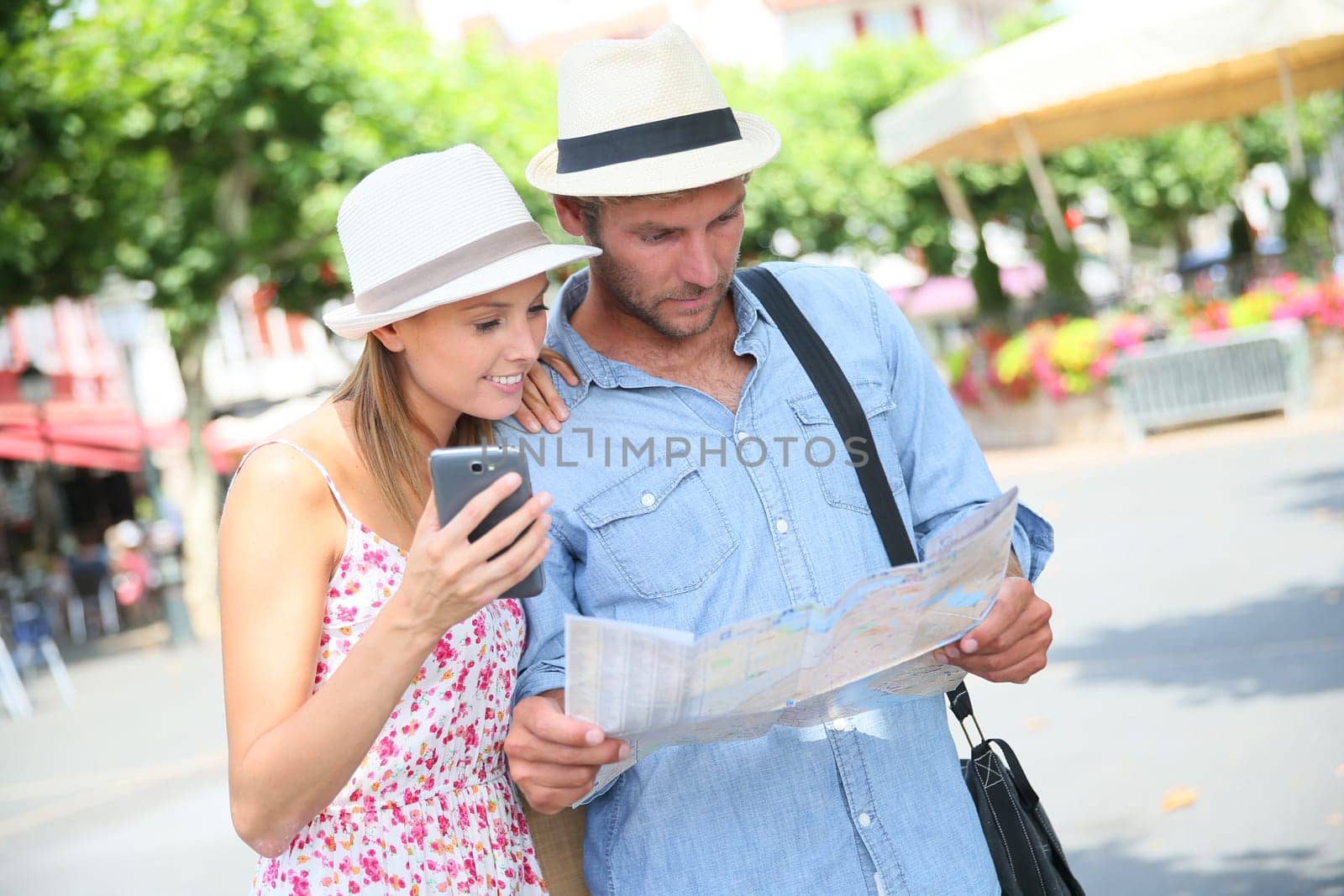 Couple of tourists looking at map in city square