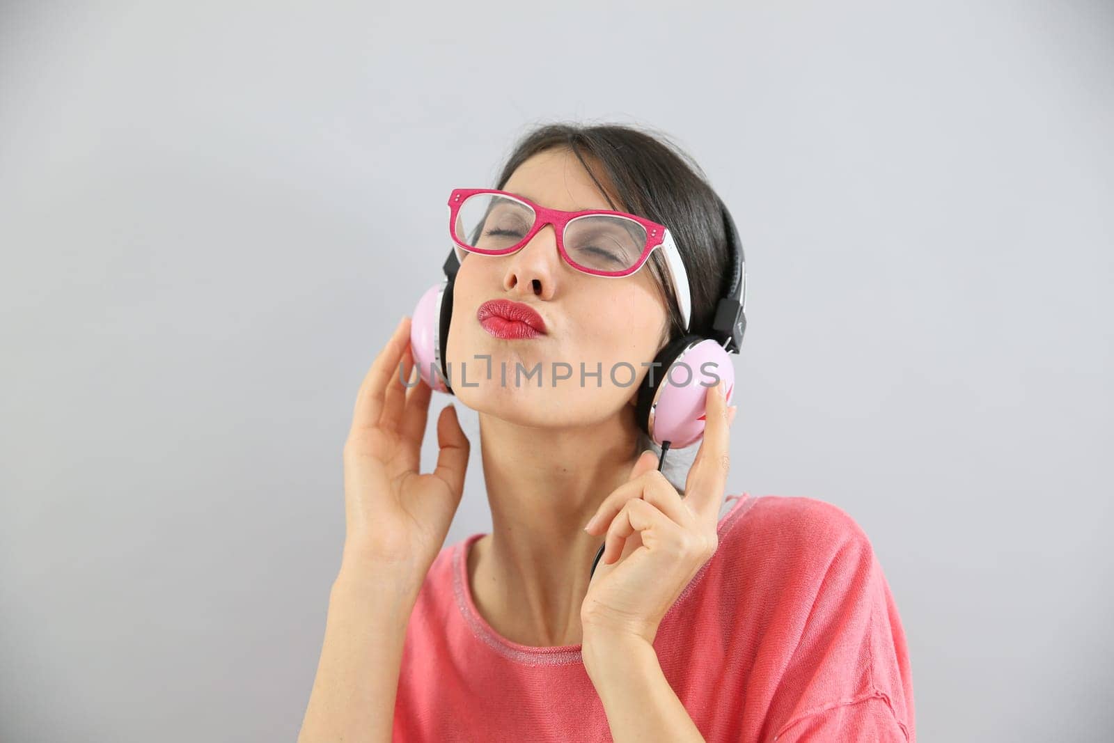 Clsoeup of brunette girl with eyeglasses using headphones