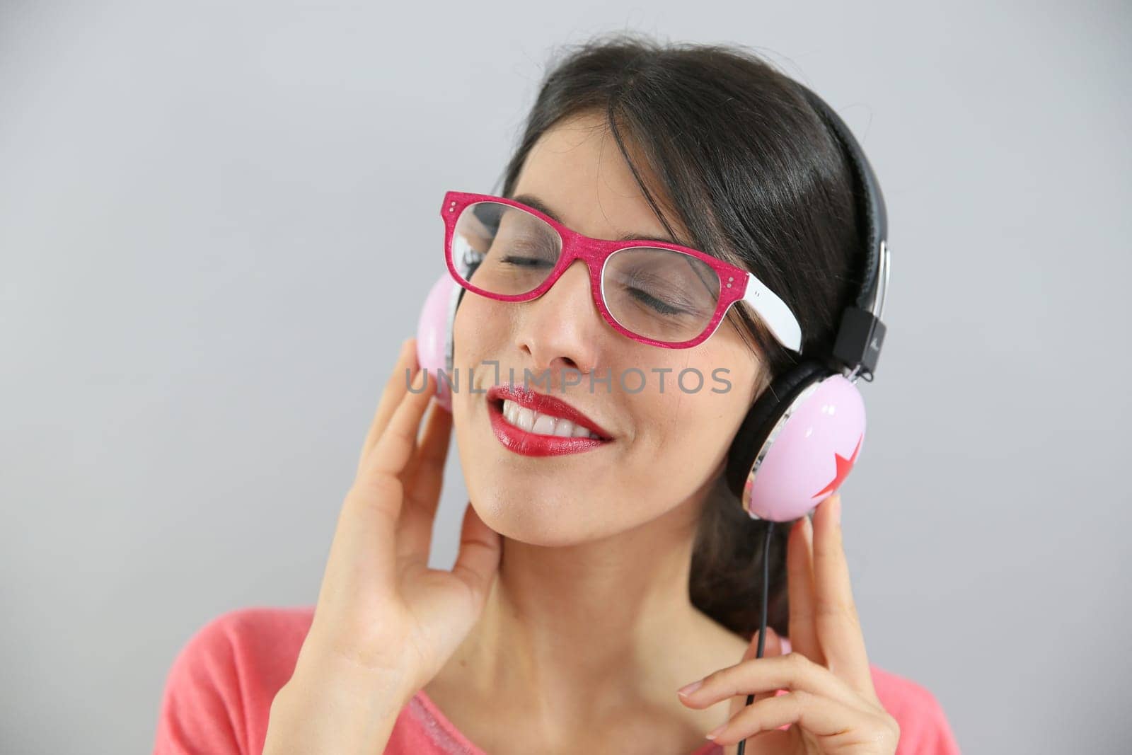 Clsoeup of brunette girl with eyeglasses using headphones