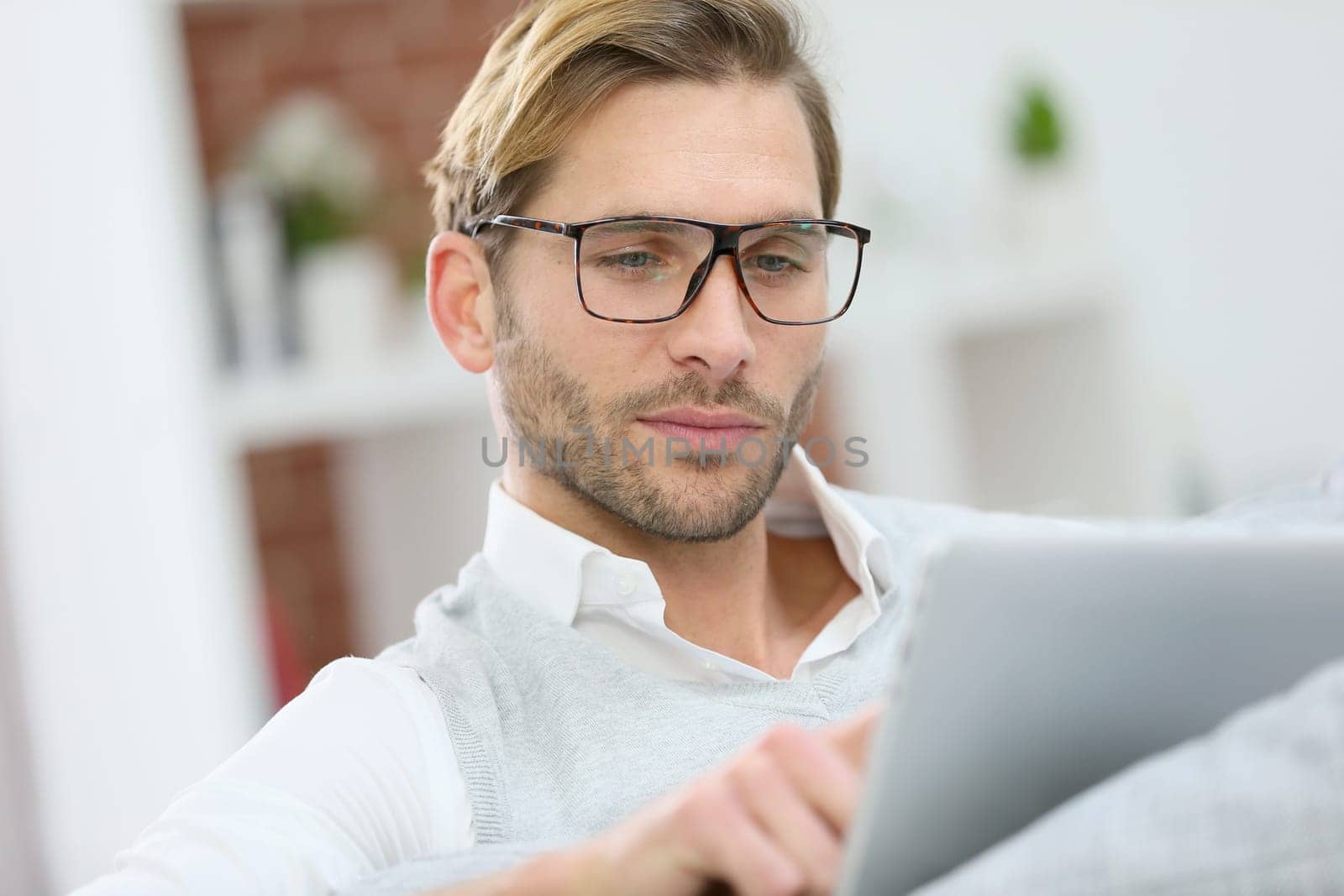 Man with eyeglasses connected on digital tablet at home