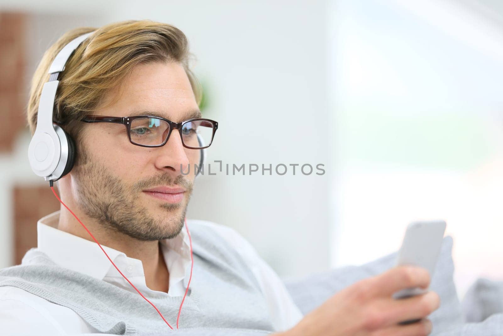 Man relaxing in sofa with smartphone and headphones
