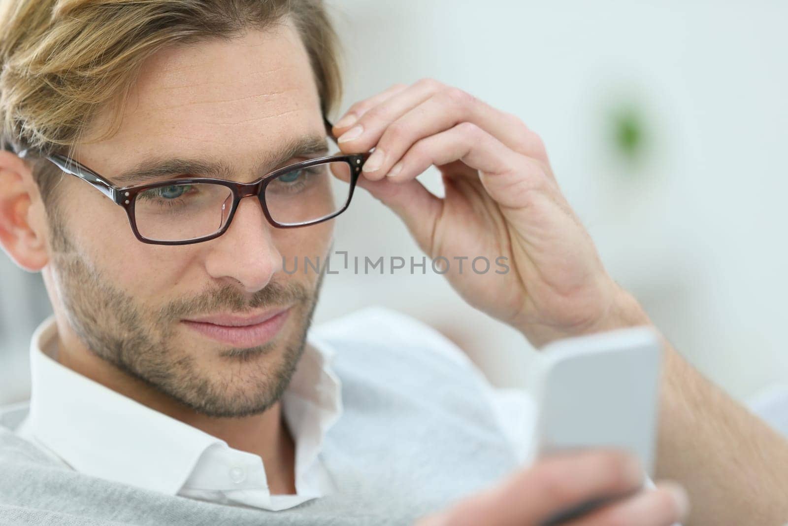 Man with eyeglasses reading message on smartphone