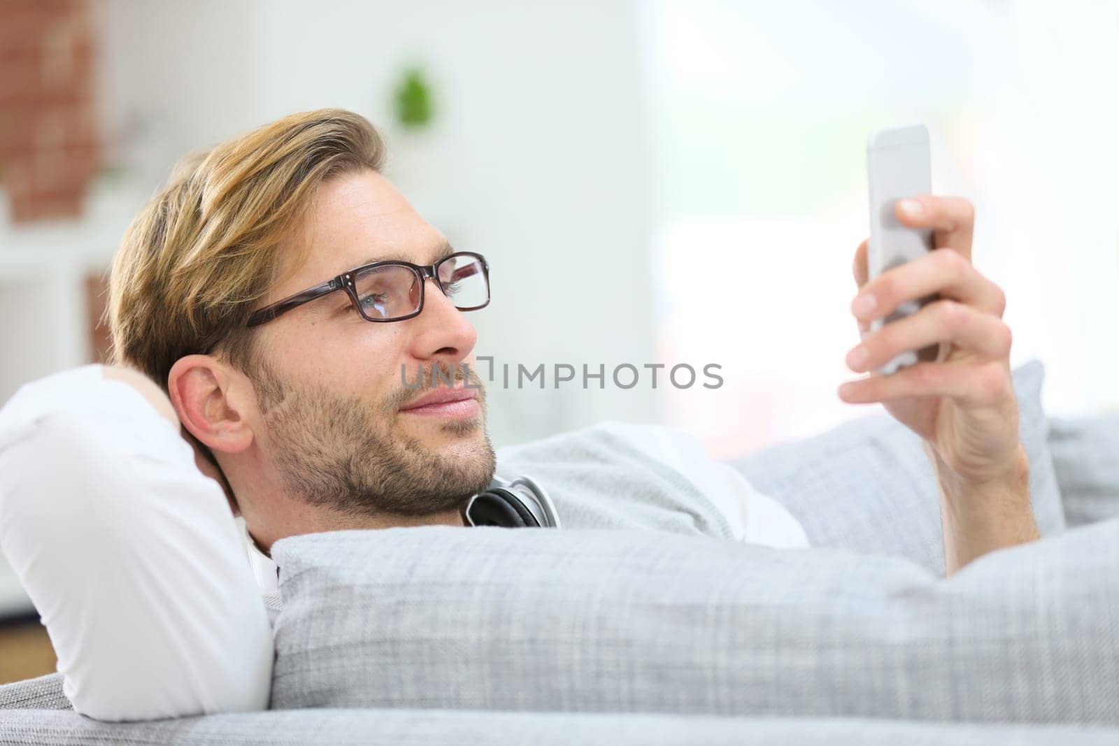Man relaxing in sofa with smartphone and headphones