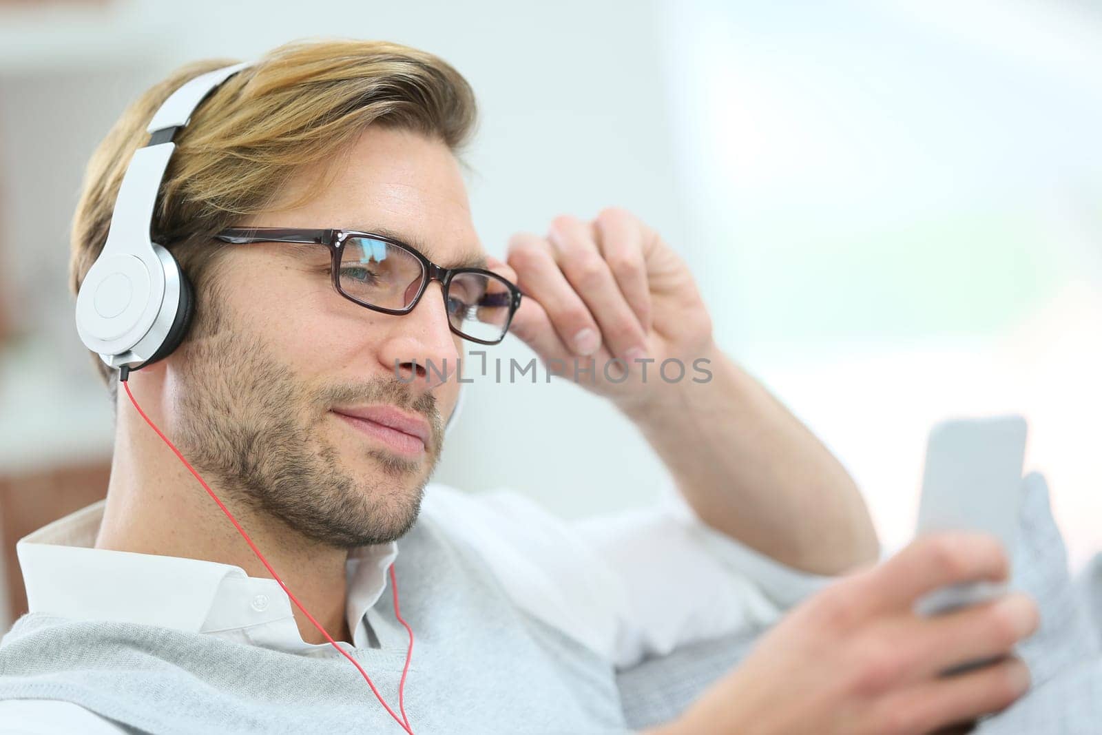 Man relaxing in sofa with smartphone and headphones