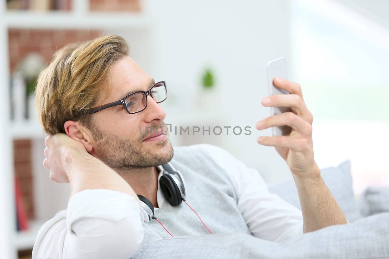Man relaxing in sofa with smartphone and headphones