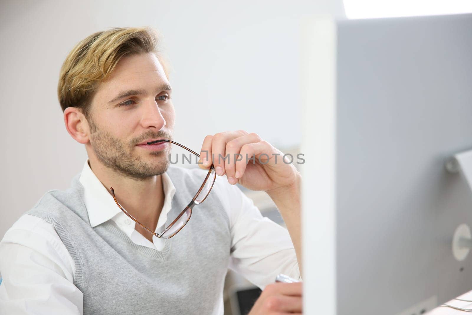 Businessman with eyeglasses sitting in front of desktop computer screen