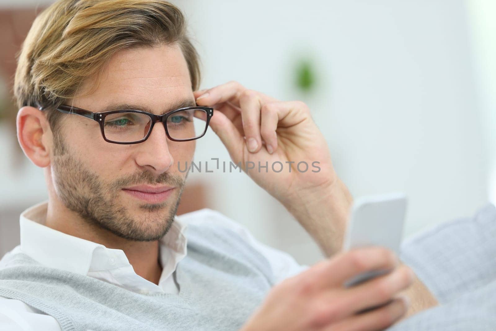 Man with eyeglasses reading message on smartphone