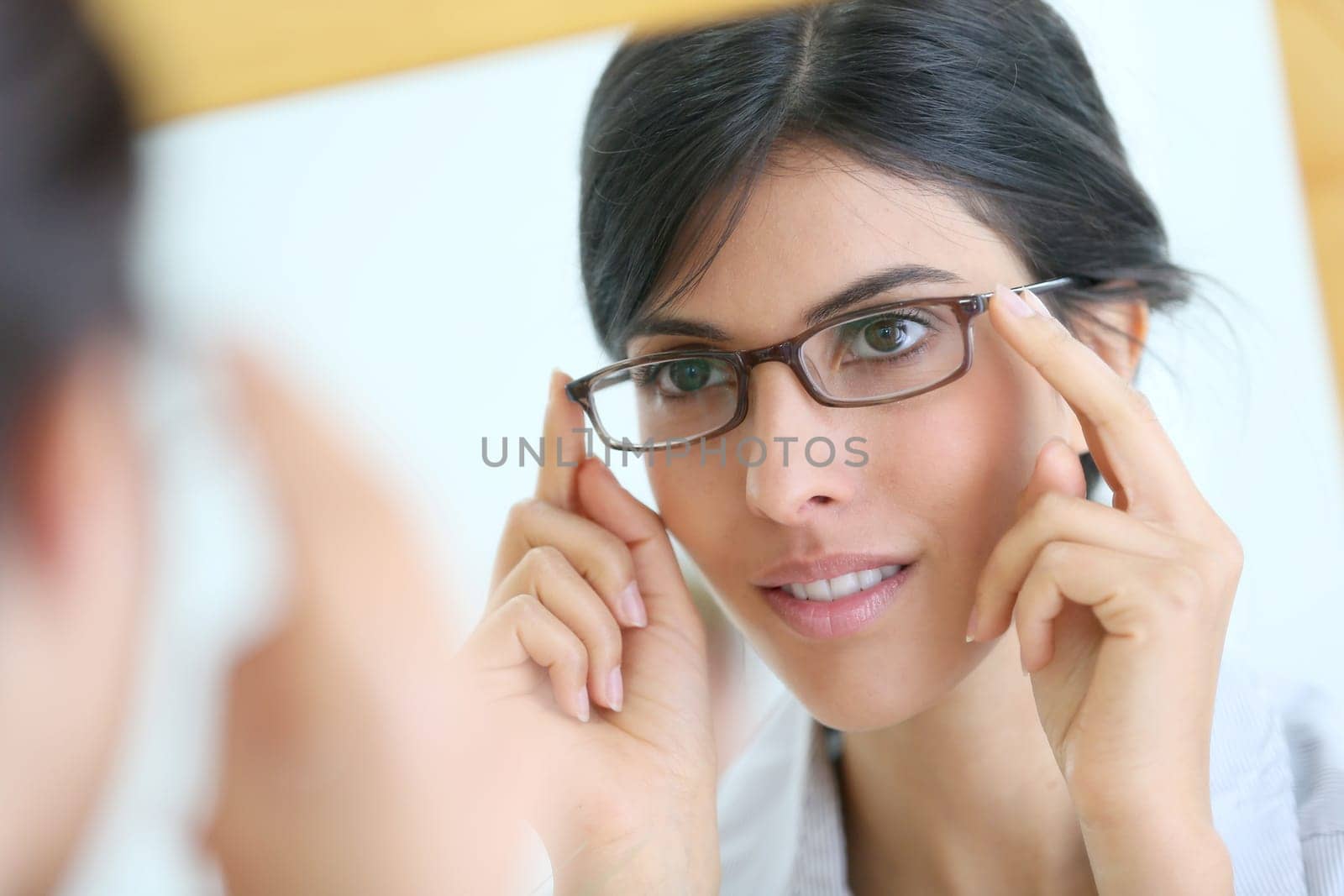Portrait of young brunette woman trying eyeglasses on