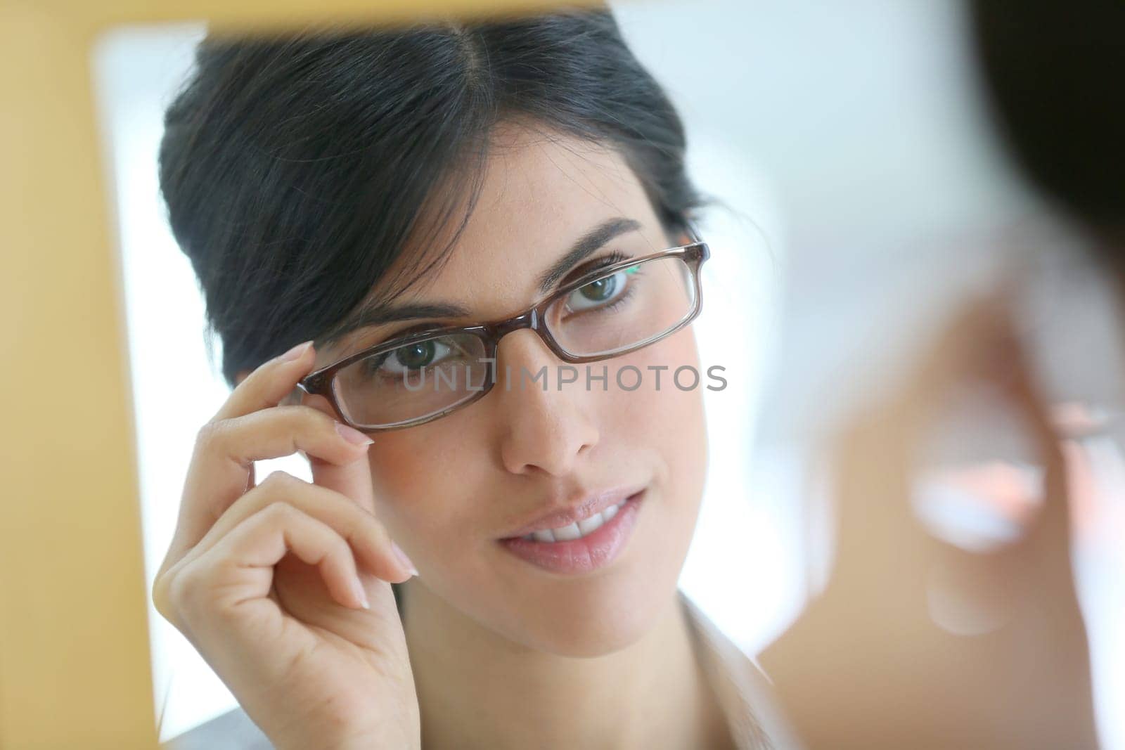 Portrait of young brunette woman trying eyeglasses on