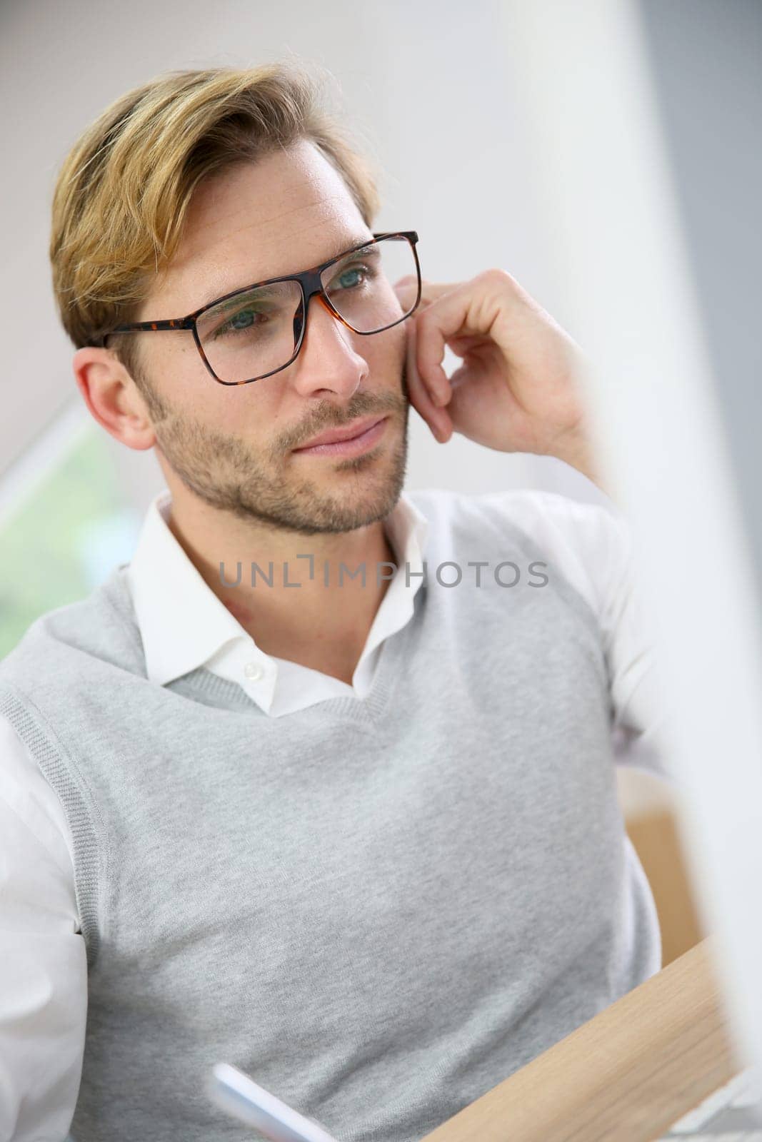Businessman with eyeglasses sitting in front of desktop computer screen