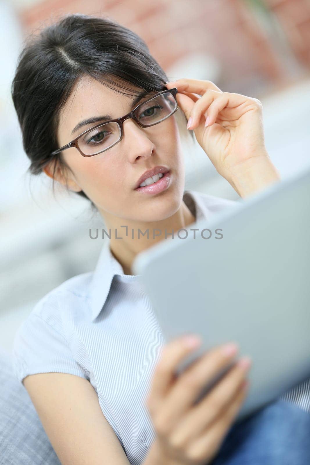 Young woman with eyeglasses using digital tablet