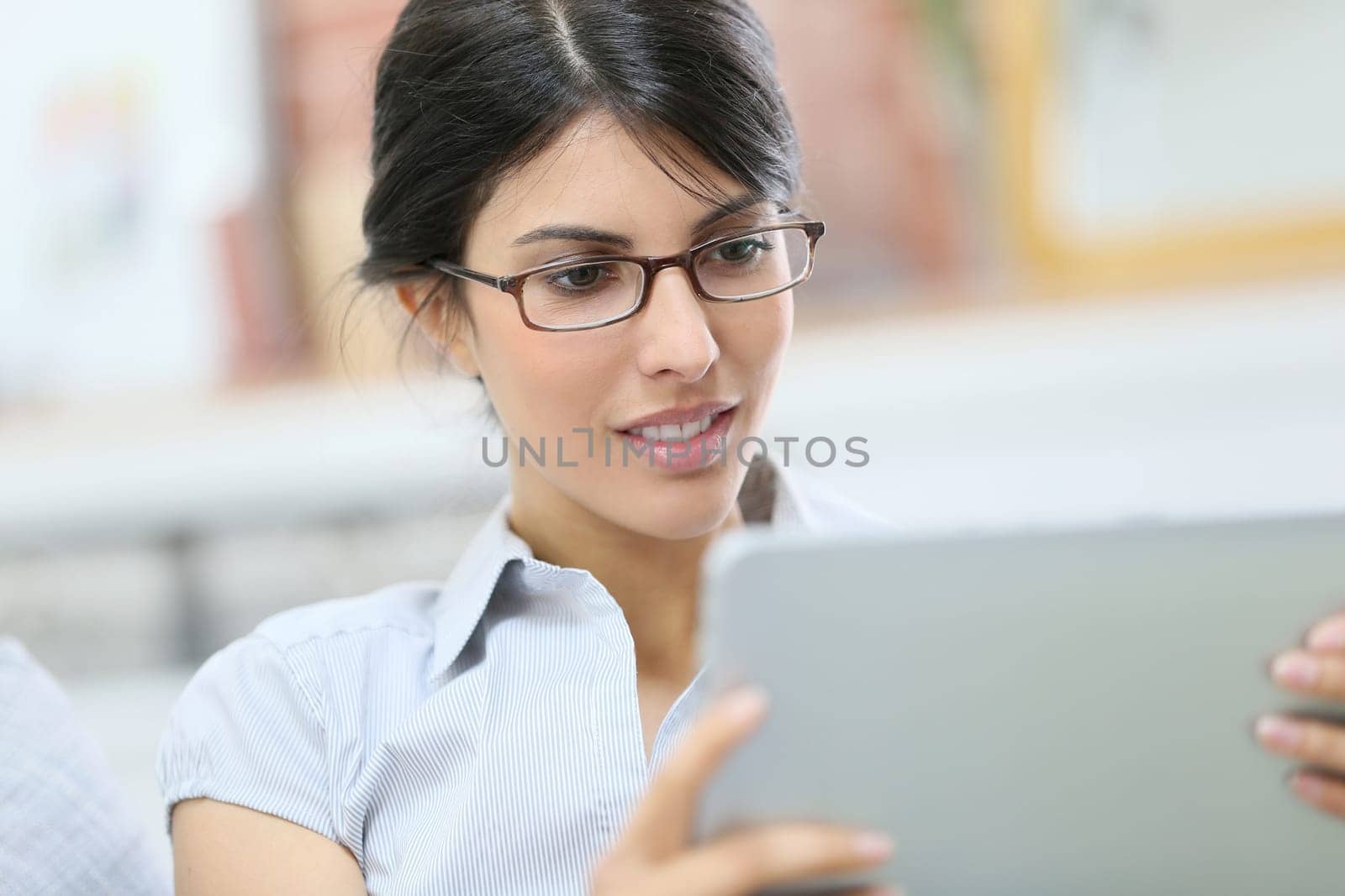Young woman with eyeglasses using digital tablet