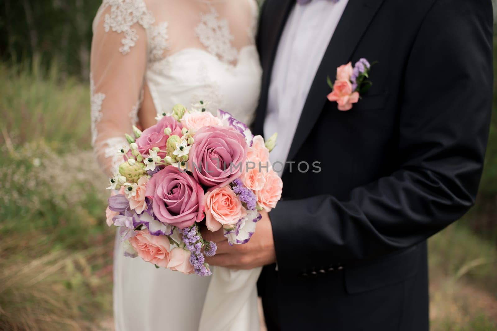 wedding couple hugging, the bride holding a bouquet of flowers in her hand, the groom embracing her