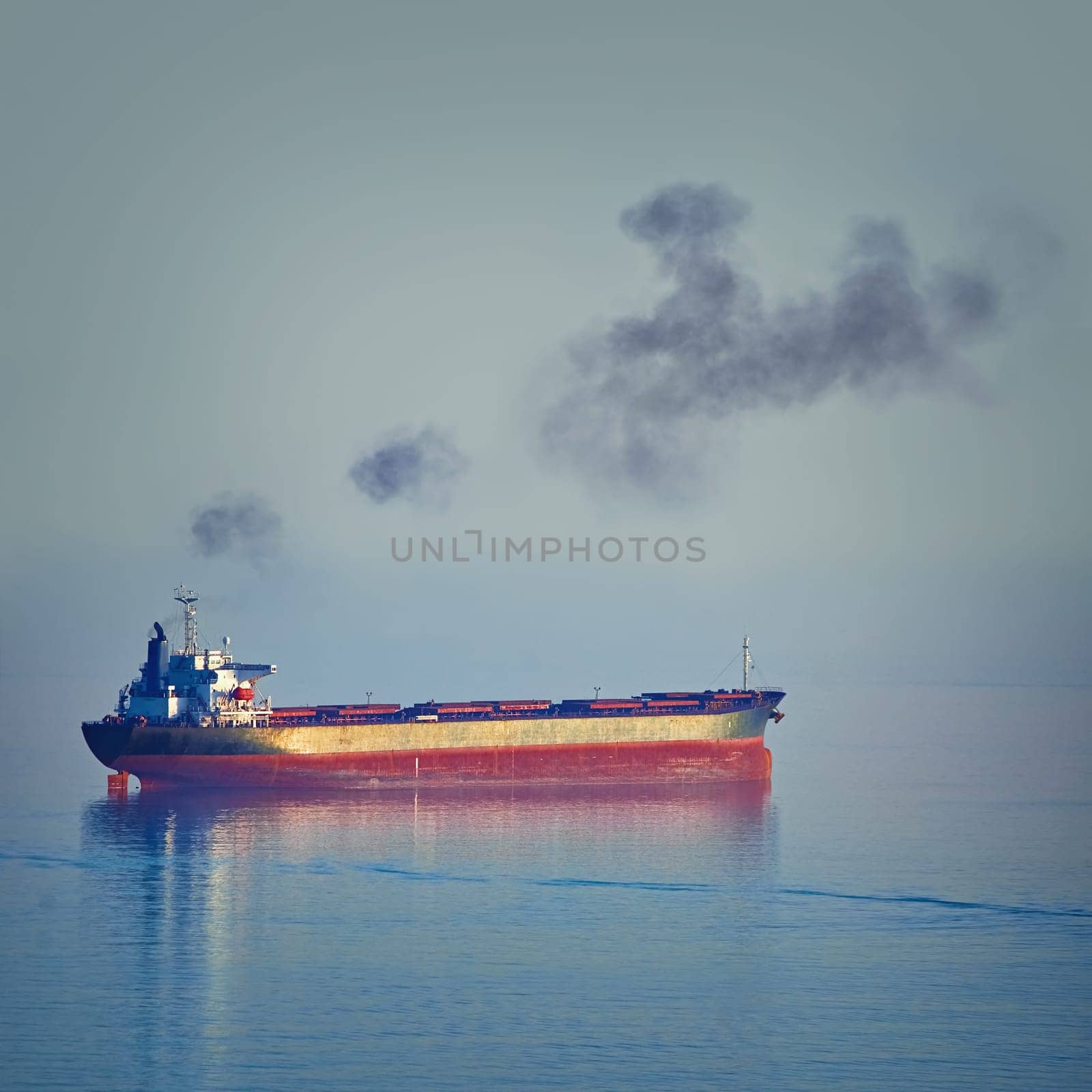 Fuming Bulk Carrier Ship in the Black Sea at the Evening