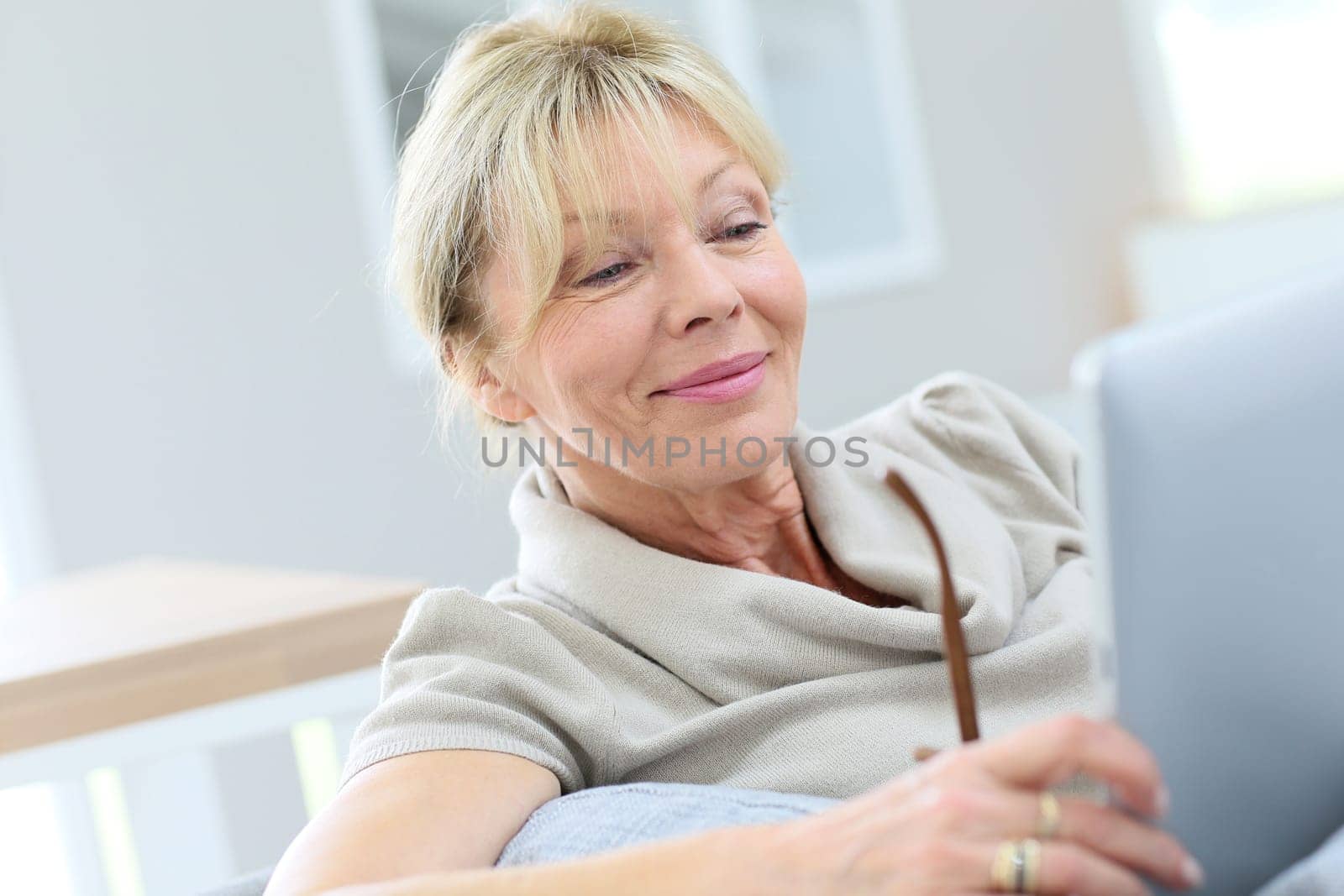 Senior woman with eyeglasses using digital tablet at home