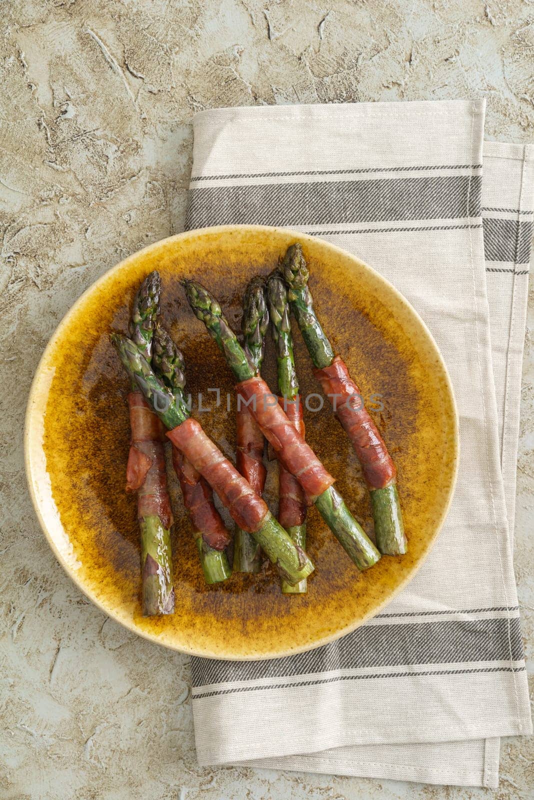 Purple asparagus wrapped with gammon on a plate