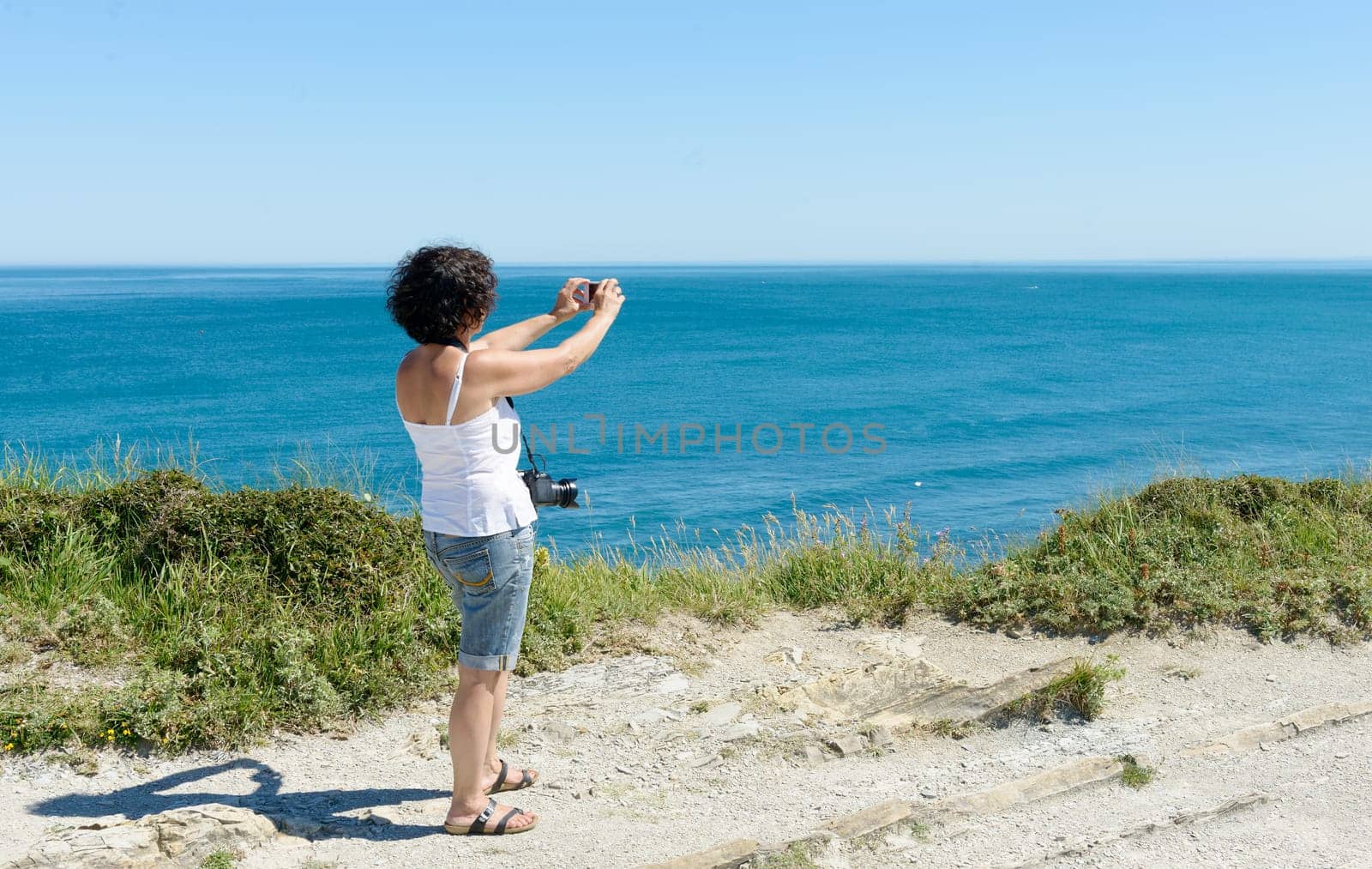 a beautiful woman takes a picture of the ocean