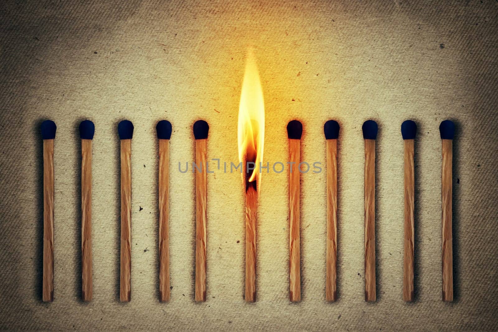 Burning match standing middle a row of whole, new matches